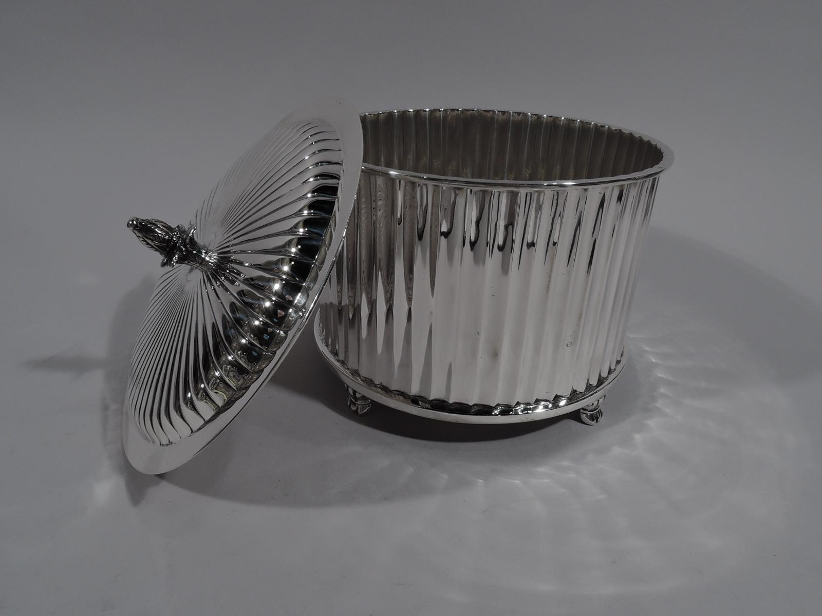 American classical sterling silver box, circa 1930. Retailed by Cartier in New York. Round and straight with columnar style fluting and ornamental supports. Cover raised with radiating gadrooning and bud finial. Marked “Cartier Sterling”. Weight: 33