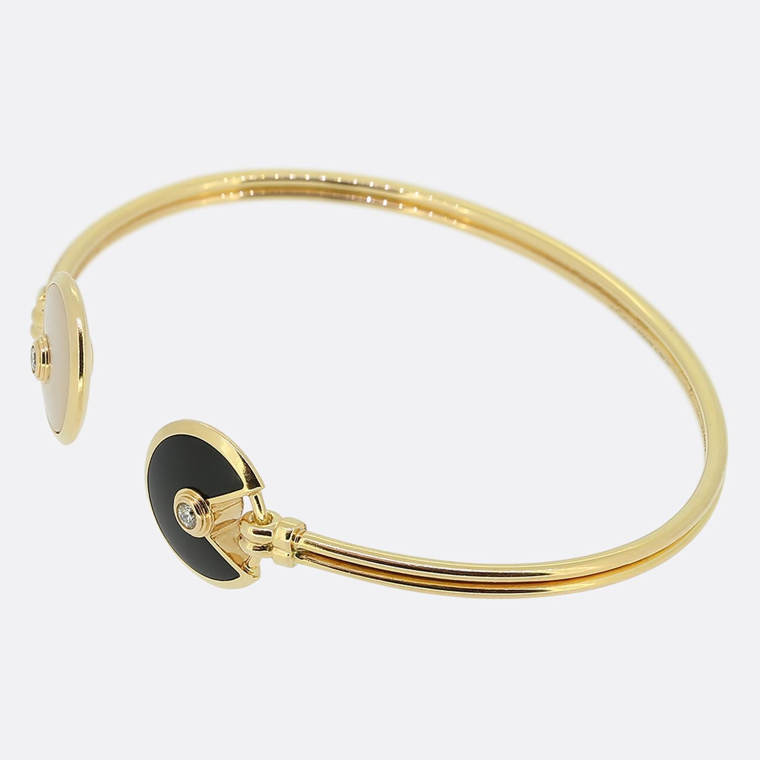 Here we have a fabulous 18ct yellow gold bracelet from the world renowned luxury jewellery house of Cartier. The piece forms part their Amulette de Cartier collection and showcases an open cuff style with iconic motif in onyx at one end and Mother