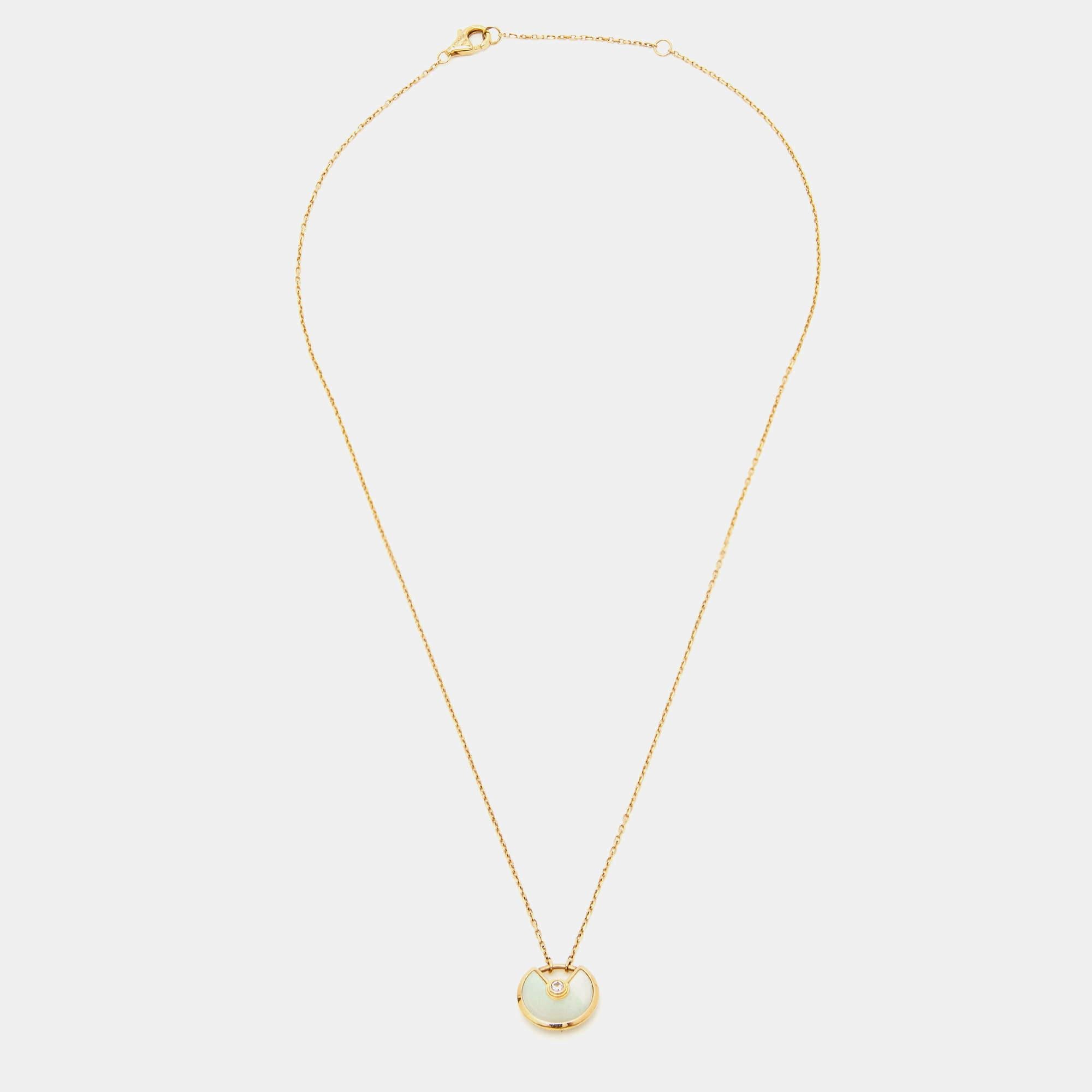 The Cartier Amulette De Cartier necklace is an exquisite piece of jewelry. Crafted in 18k yellow gold, it features a mother of pearl pendant adorned with a single dazzling diamond. The delicate design exudes elegance and sophistication, making it a