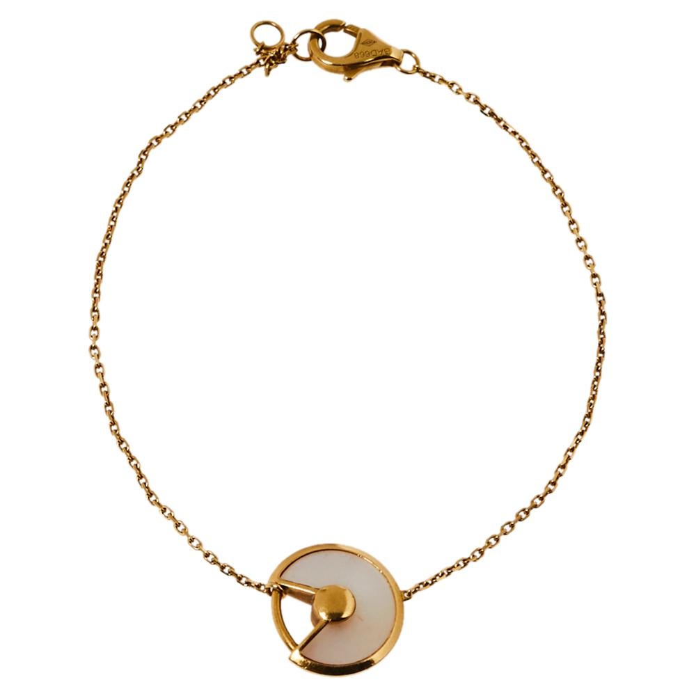 A magnificent offering from Cartier's Amulette de Cartier line. The bracelet comes sculpted from 18k yellow gold and it has the signature motif in a mother of pearl highlighted by a shimmering diamond. Smoothly finished, the desirable creation