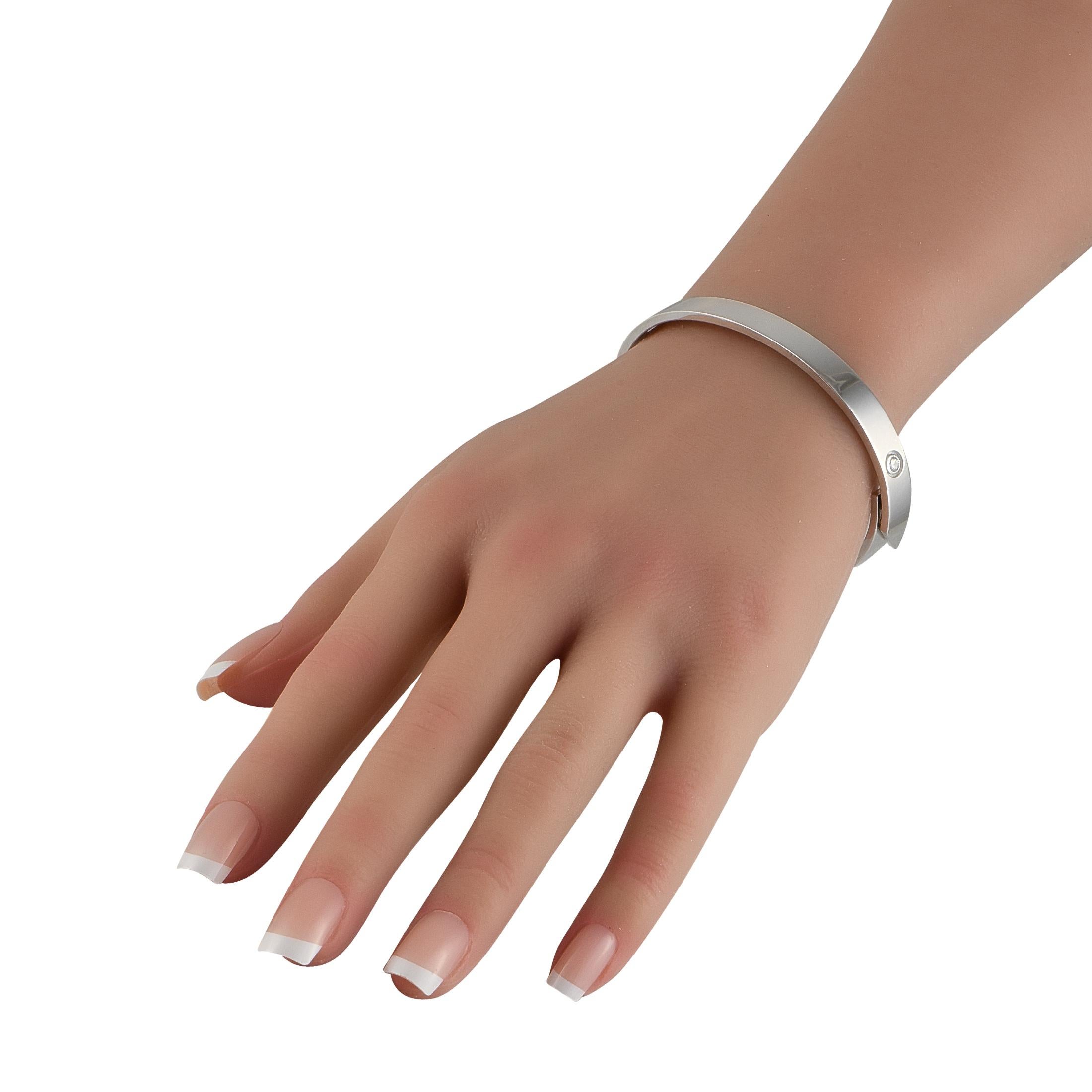 Este brazalete Cartier Aniversario, limpio y clásico, realzará al instante cualquier conjunto. Fabricada en oro blanco de 18 quilates, presenta un asombroso sentido del minimalismo y un diseño con bisagras que facilita su uso. Una única piedra