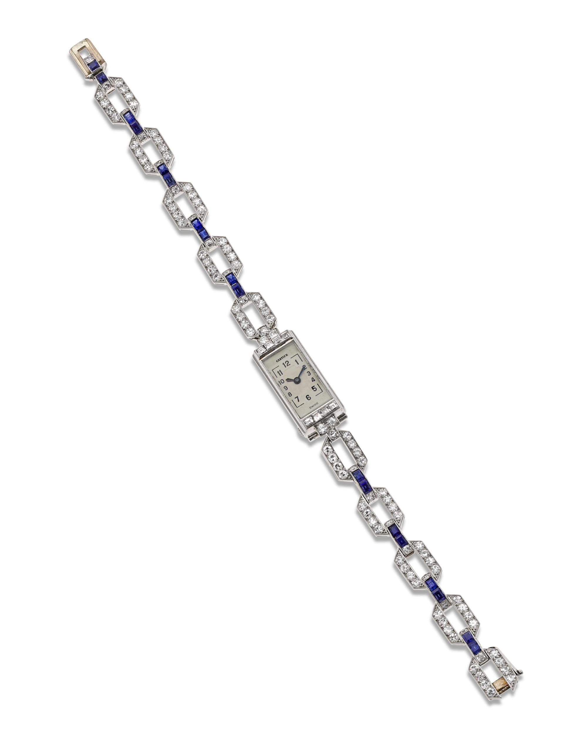 This remarkable Art Deco creation from the high-end French jeweler Cartier is a truly exceptional timepiece. An array of white diamonds adorn the watch, which is crafted of platinum in a dazzling link design. Deep blue baguette-cut sapphires connect