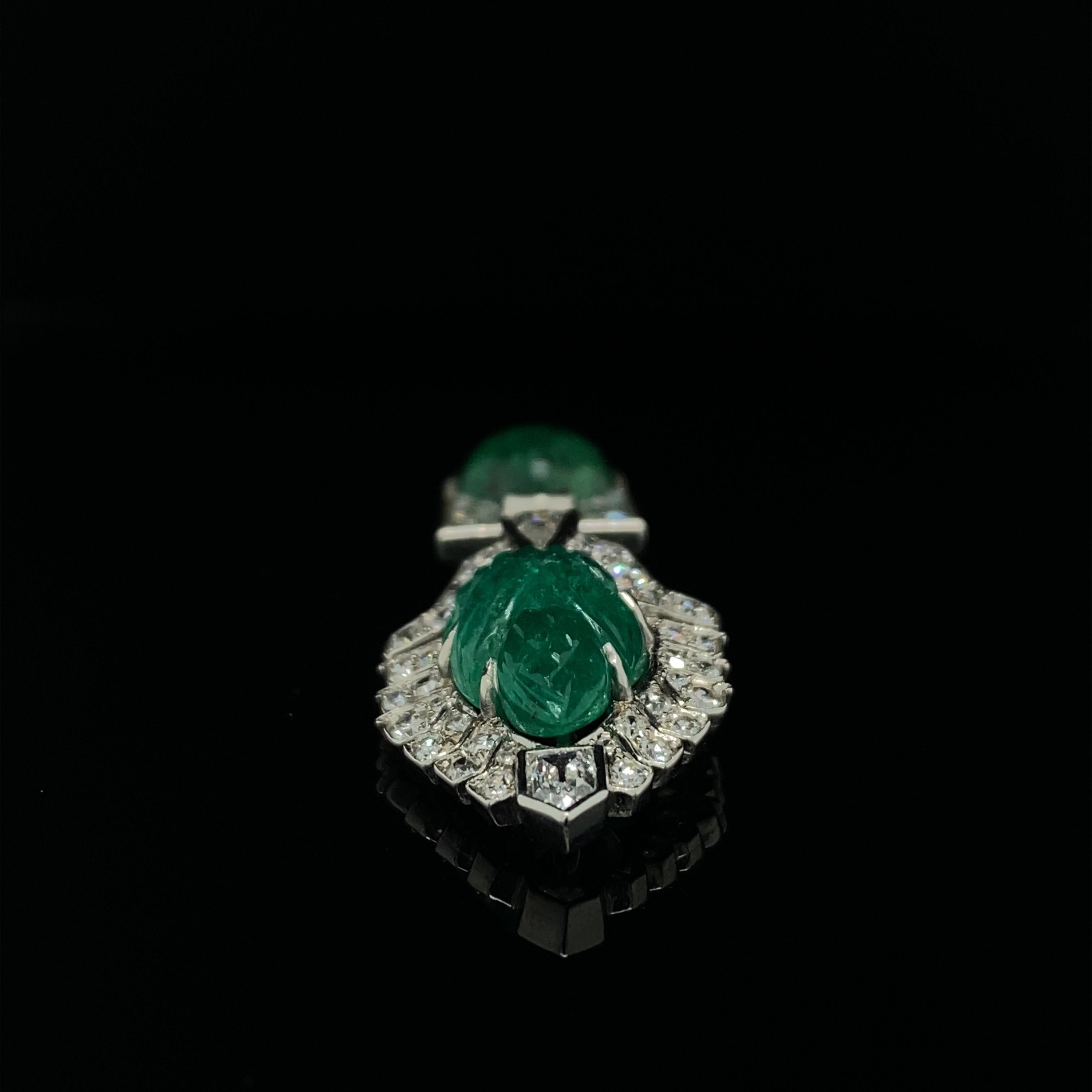 A Cartier Art Deco carved emerald and diamond jabot pin, circa 1925.

This exquisite jabot pin embodies the glamour and modish motifs of the Roaring 20s perfectly.

The top is set with a carved palmette shaped emerald enhanced by a single cut,