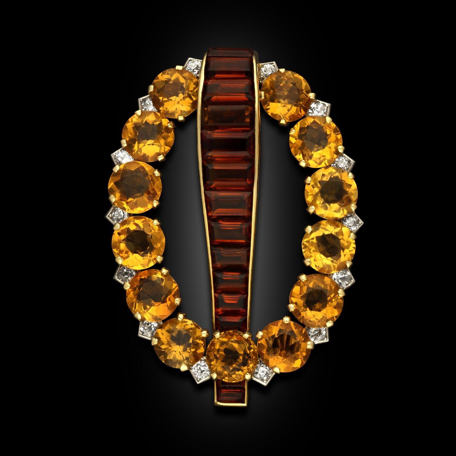 An Art Deco citrine brooch by Cartier, circa 1930. The brooch is designed as an oval of golden round cut citrines interspersed with white old cut diamonds. A tapering line of channel set calibrated madeira citrines goes down the centre. The reverse