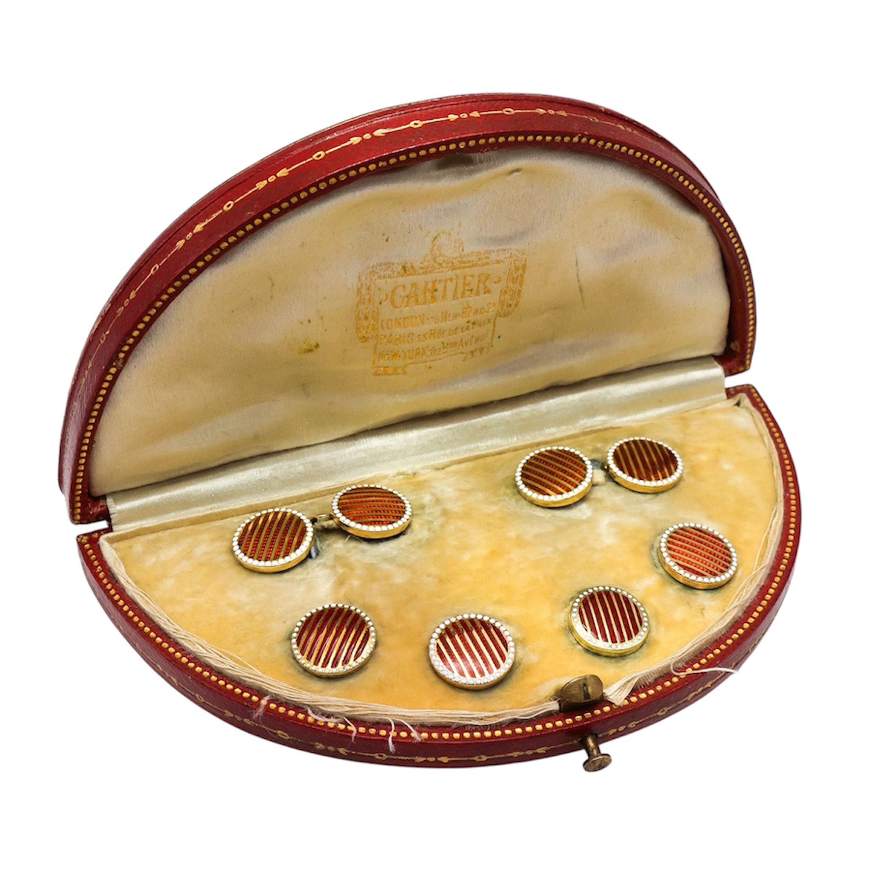 Ensemble vestimentaire pour homme en émail et or de Cartier Art déco, comprenant une paire de boutons de manchette et quatre boutons, tous avec un motif circulaire de bandes guillochées rouges, divisées par des lignes dorées, avec une bordure de
