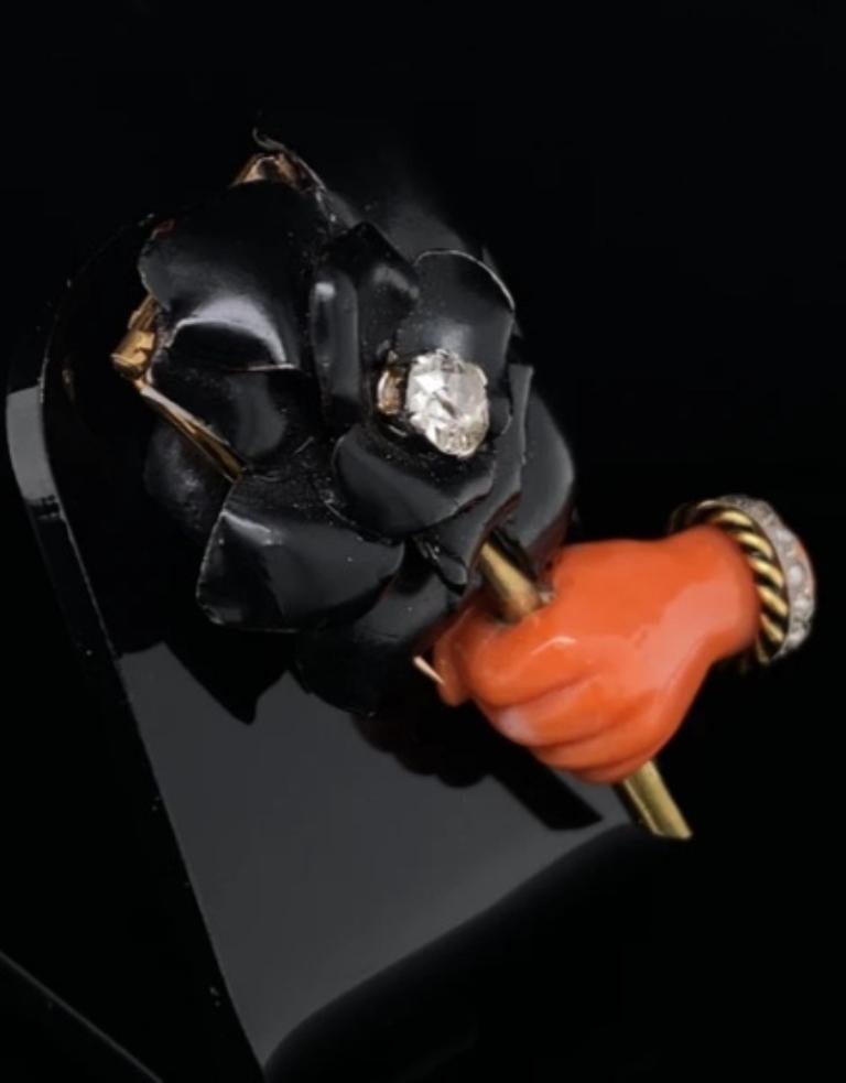 A Cartier Art Deco hand and flower pin brooch in 18 karat yellow gold and platinum.

A fun and playful piece, inspired by French Surrealism featuring a carved coral hand, wearing a stylish rose cut diamond bracelet twinned with another of enamel and
