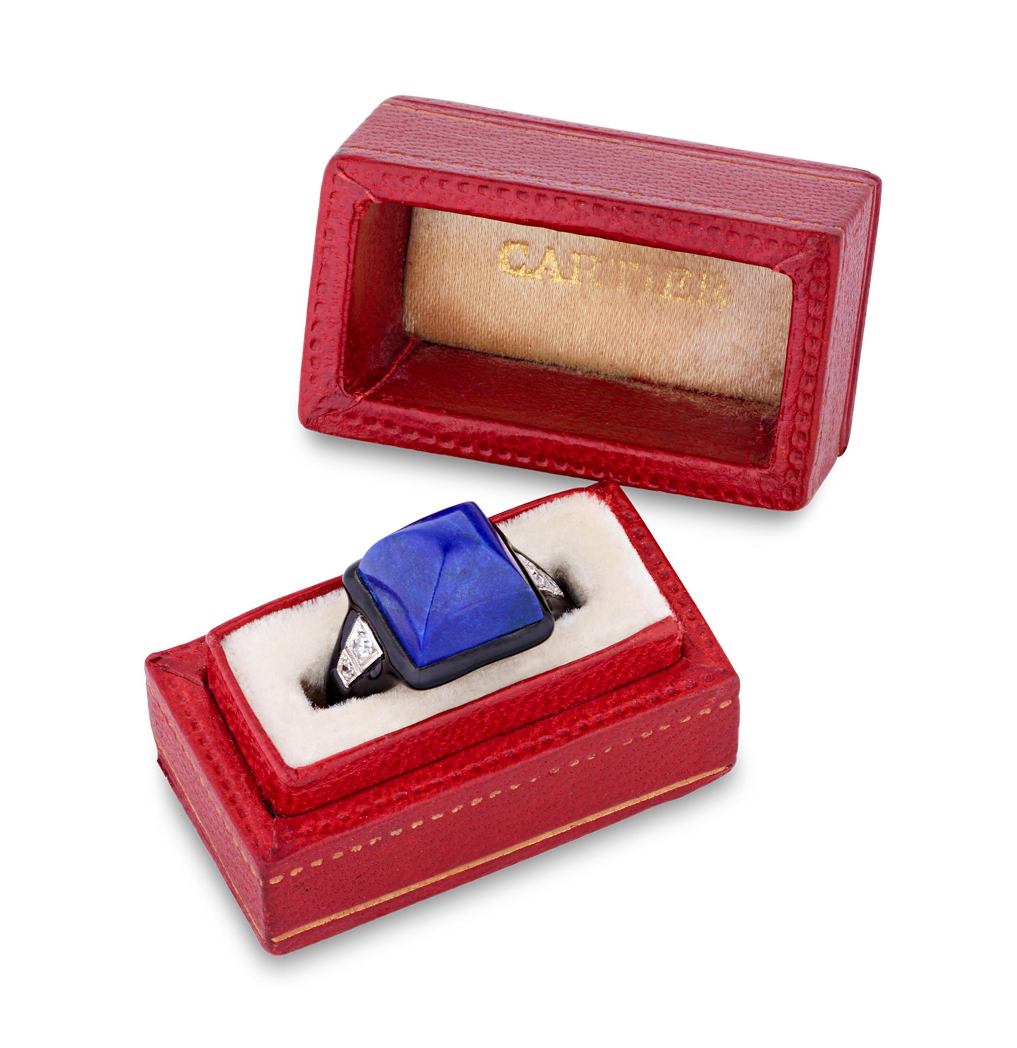 This stunning Art Deco ring by Cartier embodies timeless elegance and exceptional design. At its center is a sugarloaf cut lapis lazuli, its rich blue color accentuated by sleek black enamel. The clean, geometric lines reflect the bold