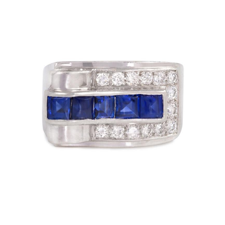 An Art Deco diamond and buff-top sapphire ring of asymmetrical geometric design, featuring an open loop on one end and a triangular diamond in the shoulder, in platinum. Cartier

Top measures approximately 1.9cm across, 11mm wide