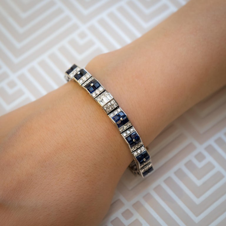 A Cartier, Art Deco, sapphire and diamond geometric bracelet, with three sets of five triangular links with groups of four, invisibly set, sapphires, on the apex, with rows of three round brilliant-cut diamonds set either side and three links, set