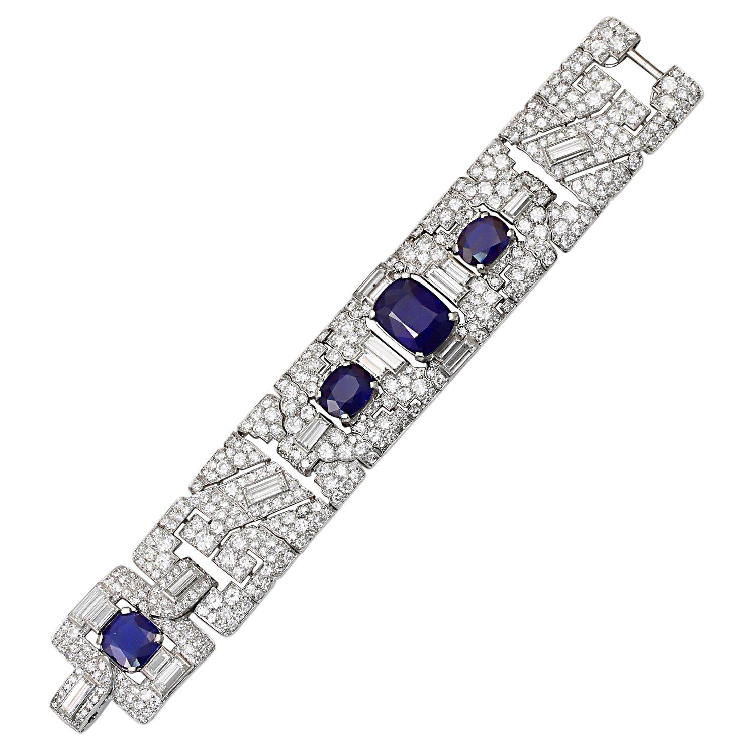 A magnificent and extremely rare art deco bracelet by Cartier, designed with a broad geometric design centering upon a large natural, no heat cushion shape sapphire accented by baguettes and old-mine diamonds extending towards two small oval shape