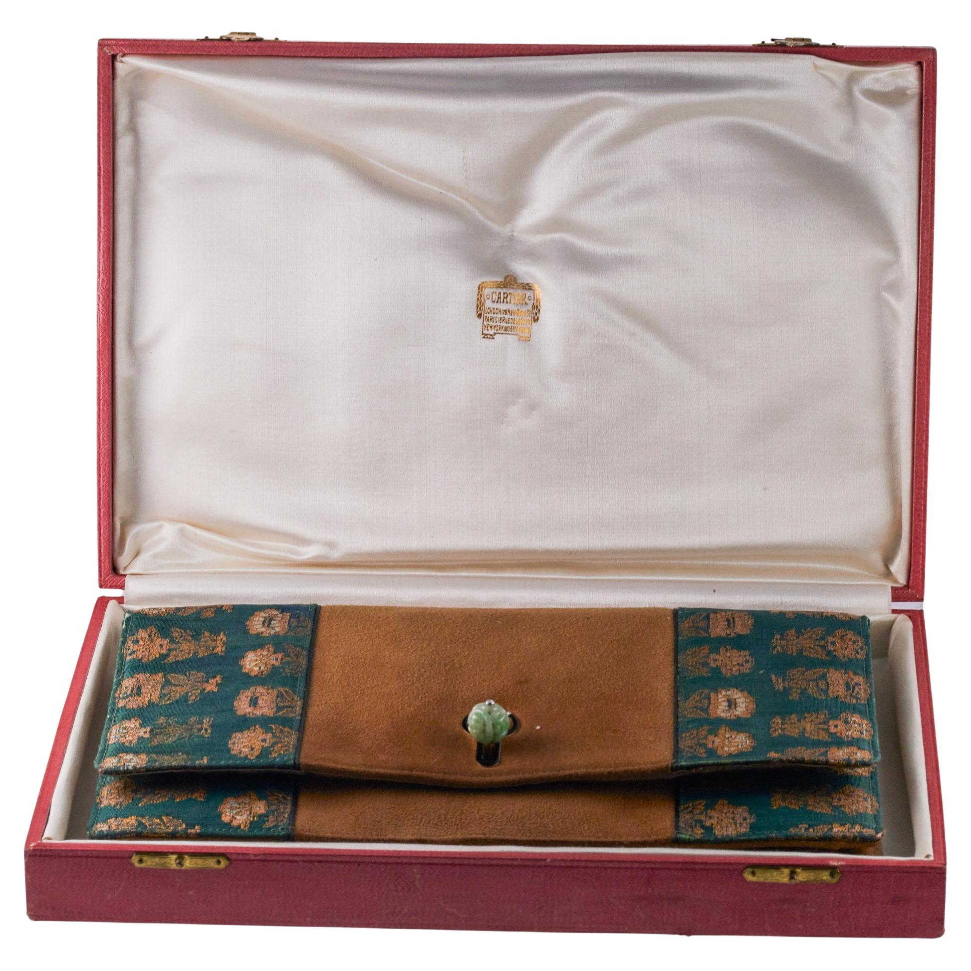 Art Deco Cartier Damenhandtasche aus Wildleder mit Stoffbesatz. Die Tasche ist mit einer Innenausstattung aus Satin versehen, mit mehreren Fächern, einem Kompaktspiegel und zwei kleinen Umschlagtaschen (abnehmbar).  Mit geschnitzter Jade und