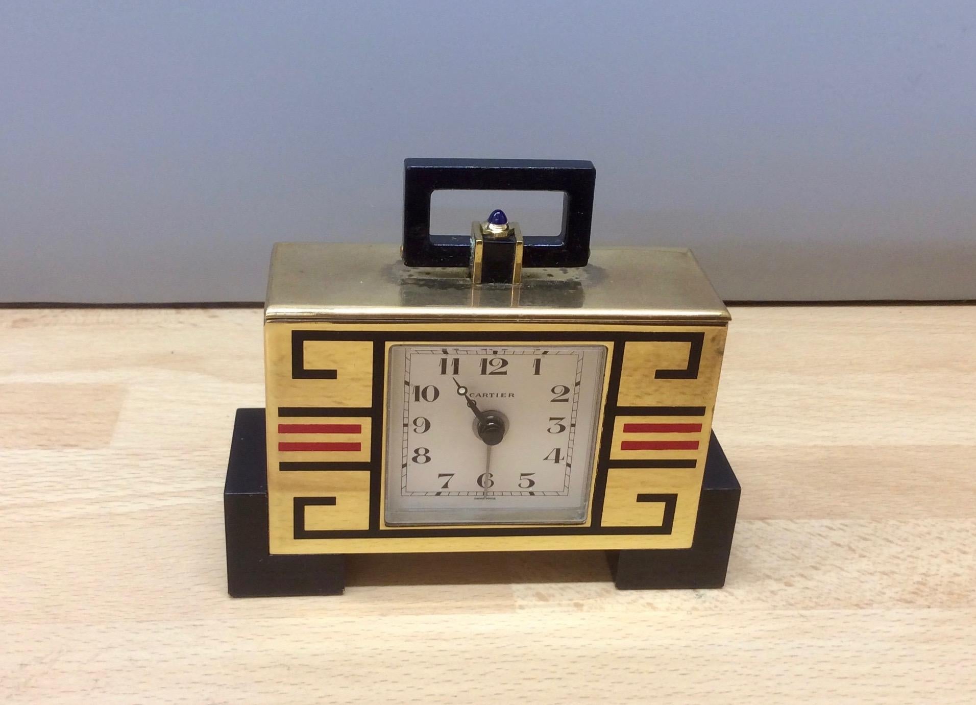Cartier

Art Deco ‘cubist’ travel clock in a gilded case resting on black block feet with black and red line decoration.

Painted dial with Arabic numerals signed ‘Cartier’, original steel moonpoise hands with luminous centers and separate hand