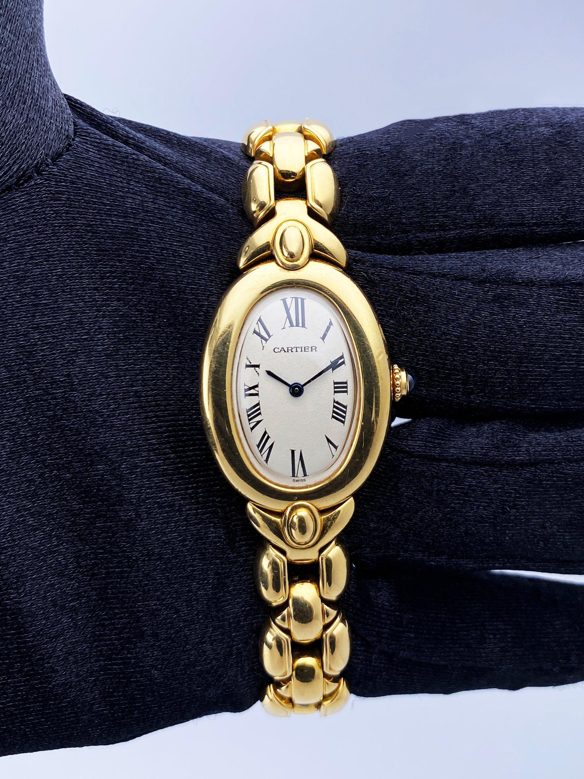 Cartier Baignoire 2311 Ladies Watch. 23mm 18K yellow gold case with 18K yellow gold bezel. Off-white dial with blue hands and black Roman numeral hour markers. 18K yellow gold bracelet with hidden butterfly clasp. Will fit up to 6-inch wrist.