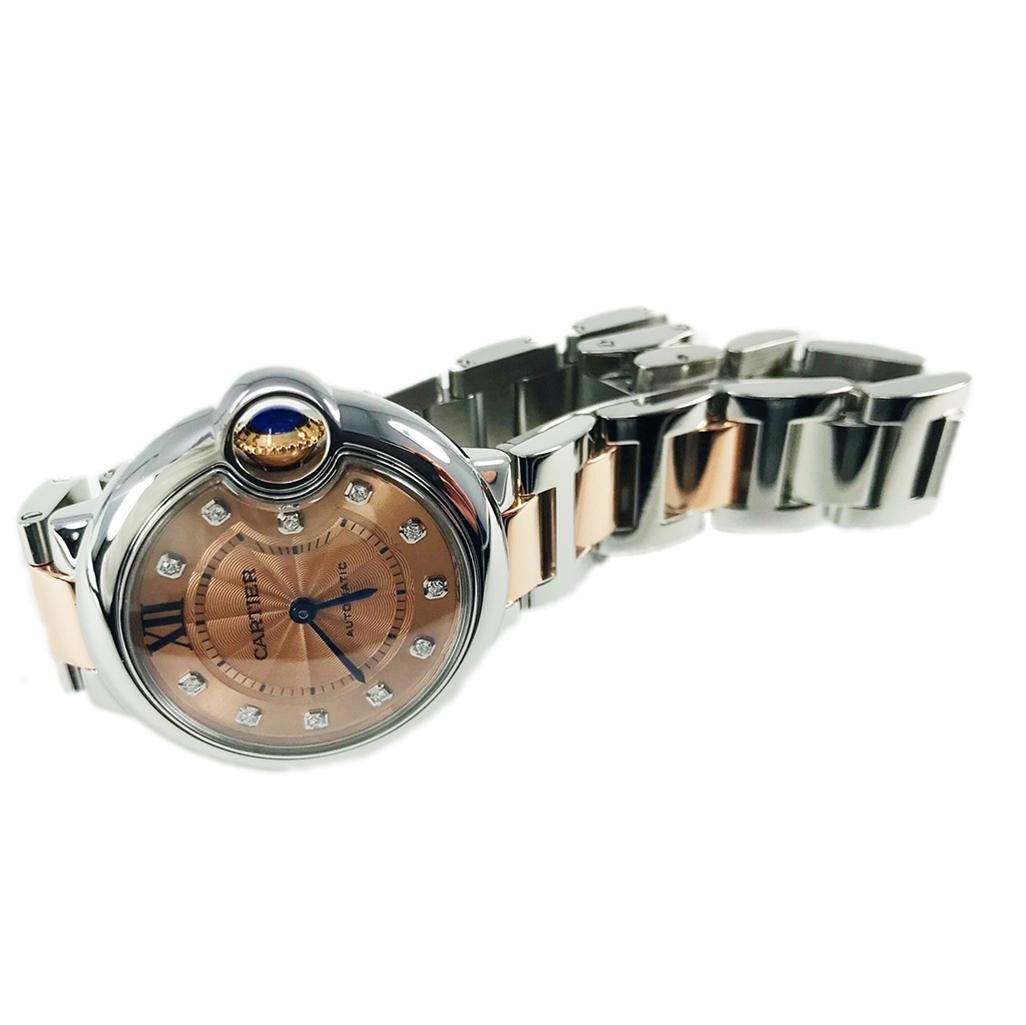 Cartier Ballon Bleu Watch, ref. WE902053. This certified pre-owned Cartier timepiece has a 33mm stainless steel case with an 18k rose gold and stainless steel bracelet. The 18k rose gold crown set has a blue cabochon sapphire. The 18K rose gold