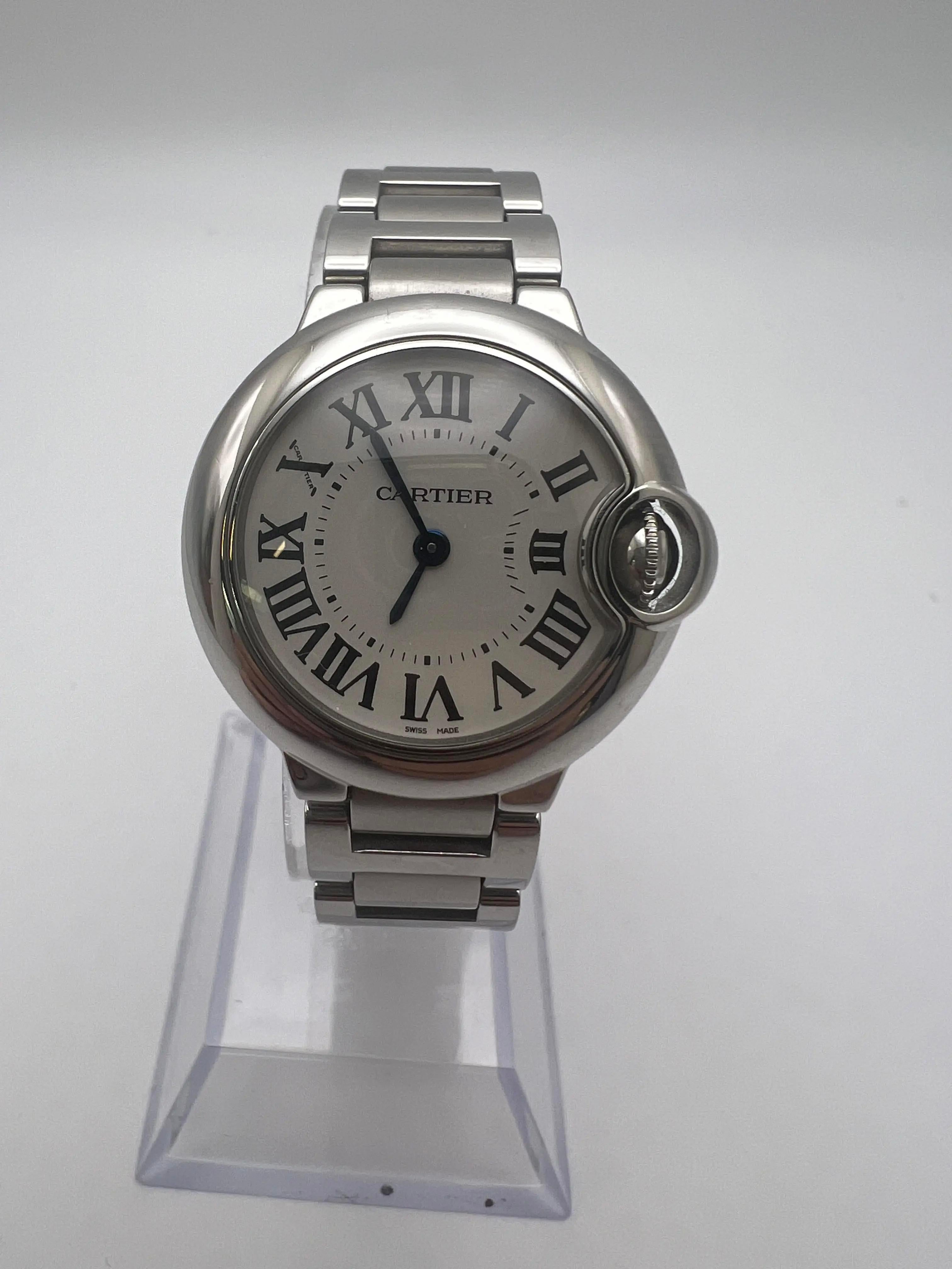Cartier Ballon Bleu in condizioni perfette, referenza W69010Z4. Questo elegante orologio presenta una cassa in acciaio inossidabile da 28 mm con un design arrotondato che incarna lo stile tipico di Cartier. Il quadrante bianco è impreziosito da
