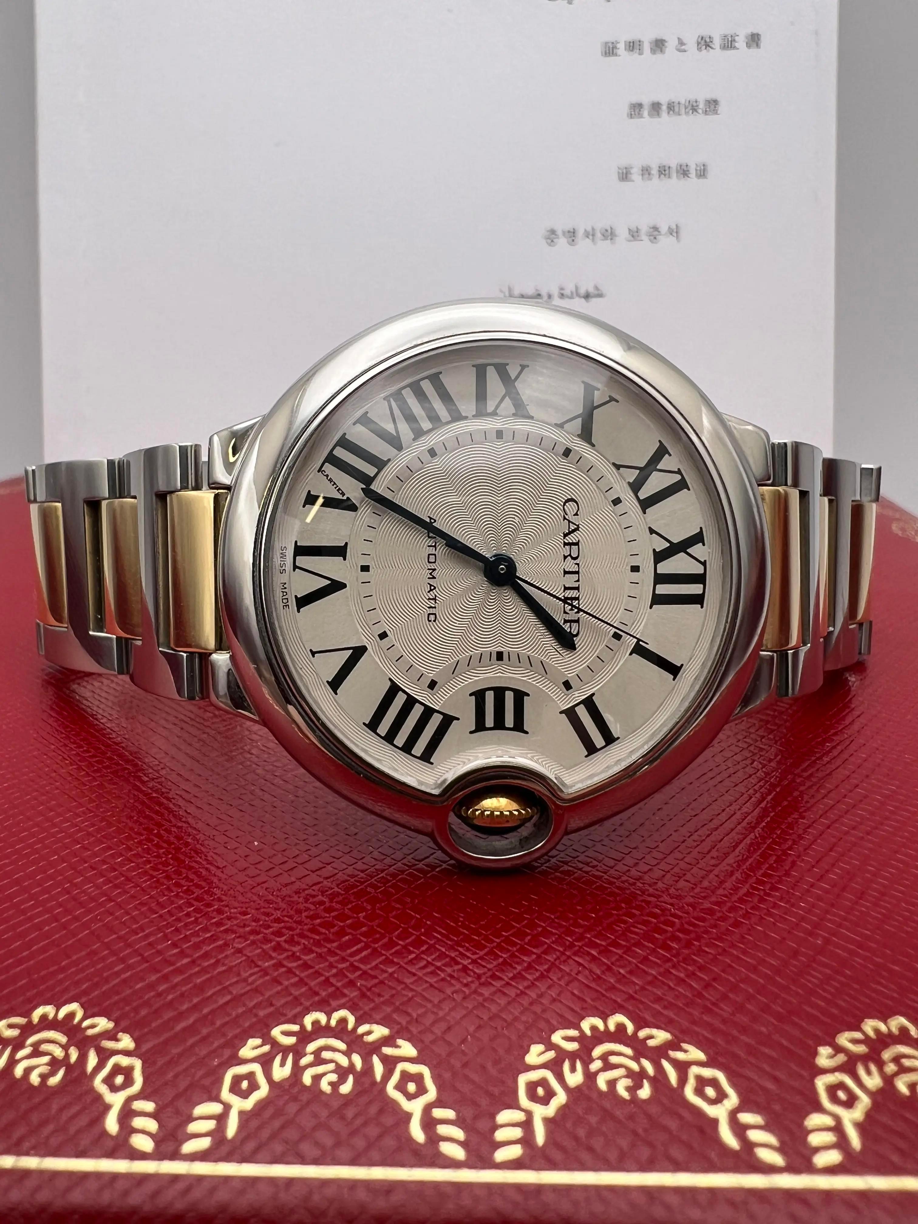 Cartier Ballon Bleu 36 mm modelo W6920047 en perfecto estado. Pulsera bicolor de oro amarillo de 18 quilates y acero, con esfera plateada con números romanos negros, manecillas de espada azules y ventanilla de fecha a las 3. Corona de oro con