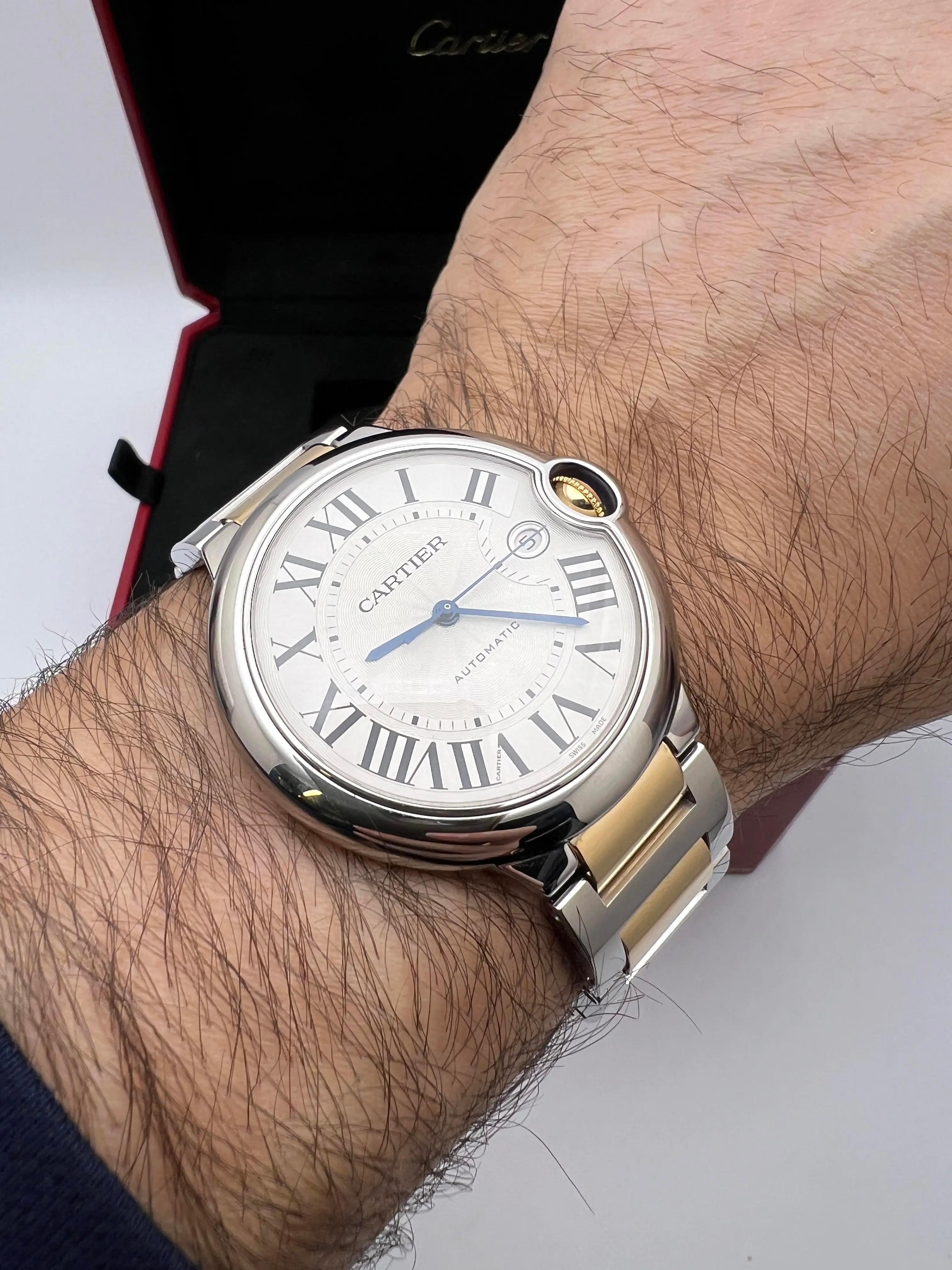 The Cartier Ballon Bleu, reference W69009Z3, features a 42mm stainless steel case accented with an 18K yellow gold fluted crown set with a blue synthetic cabochon, embodying Cartier's signature elegance. The silver guilloché dial showcases bold