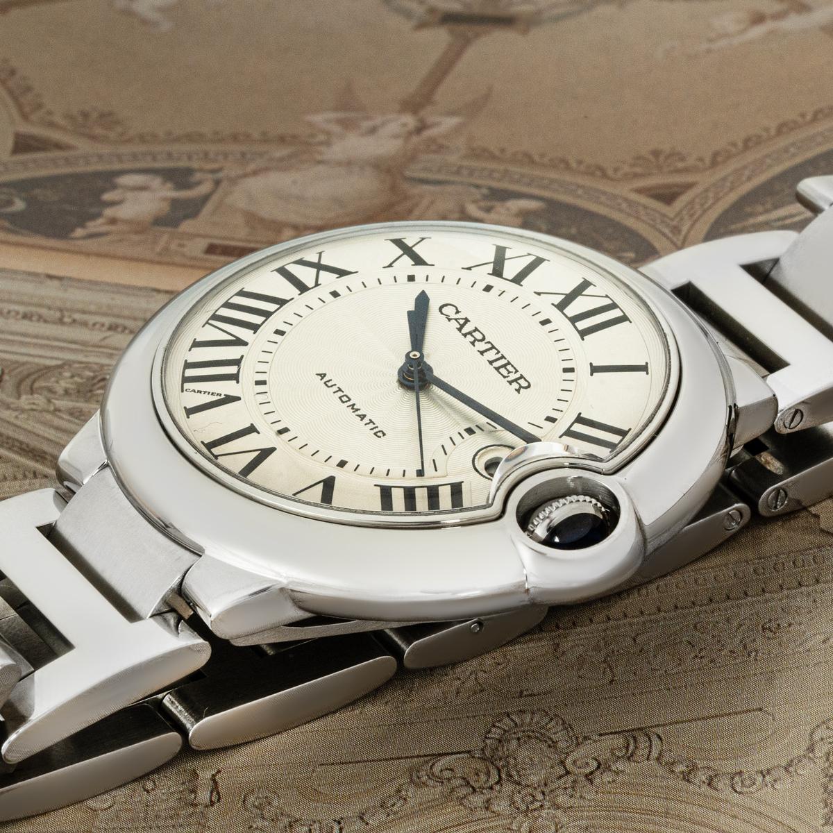 A 42mm Ballon Bleu from Cartier in stainless steel. Featuring a silvered guilloche dial with roman numerals, a date display, blued-steel sword-shaped hands, and a Cartier signature hidden at VII. The watch features a fixed stainless steel bezel and