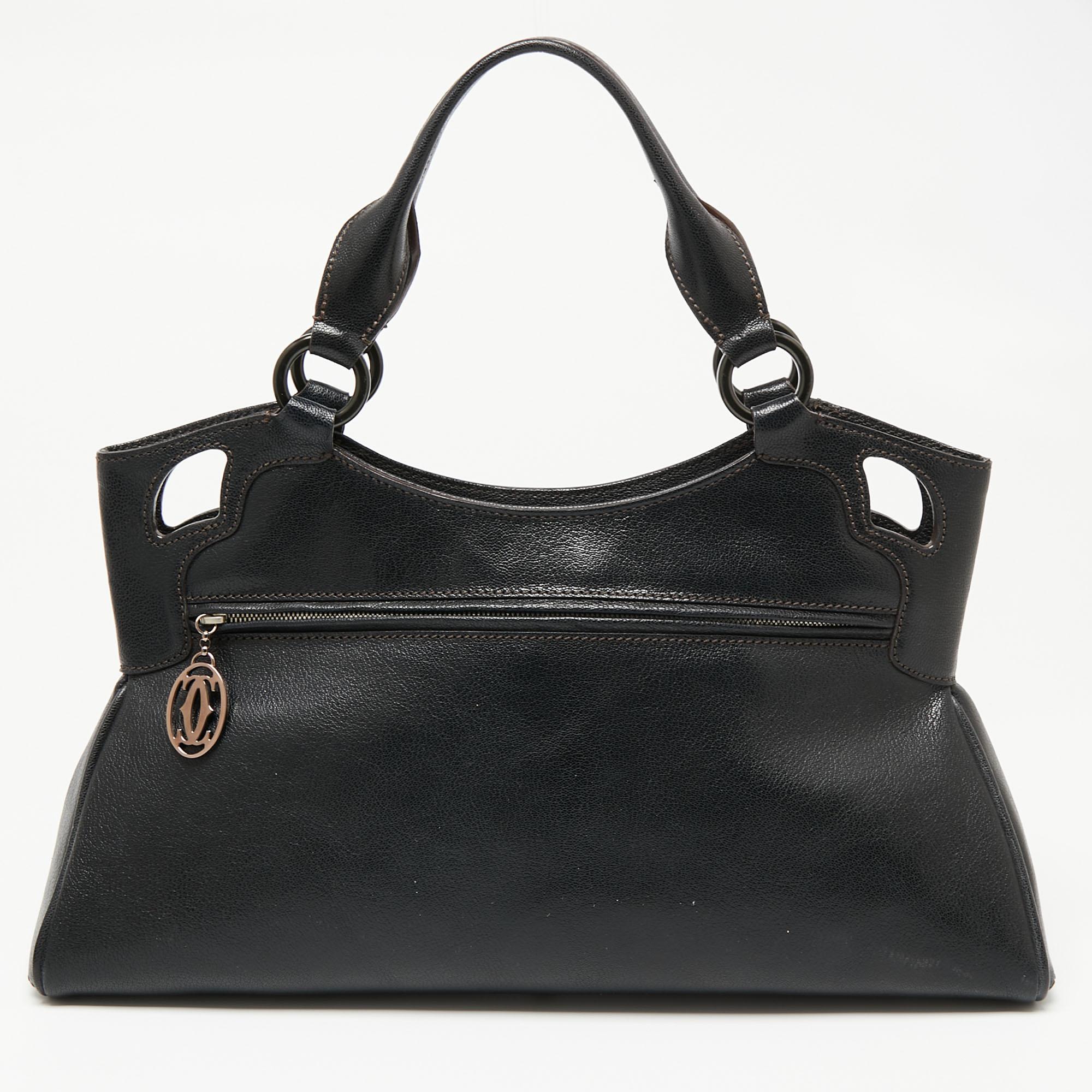 This Cartier beauty arrives in a gorgeous shape and design. It has a black leather body with the logo detailing on the exterior and is held by two handles. The zipper secures the fabric interior and overall, the bag looks ready to lift your classic