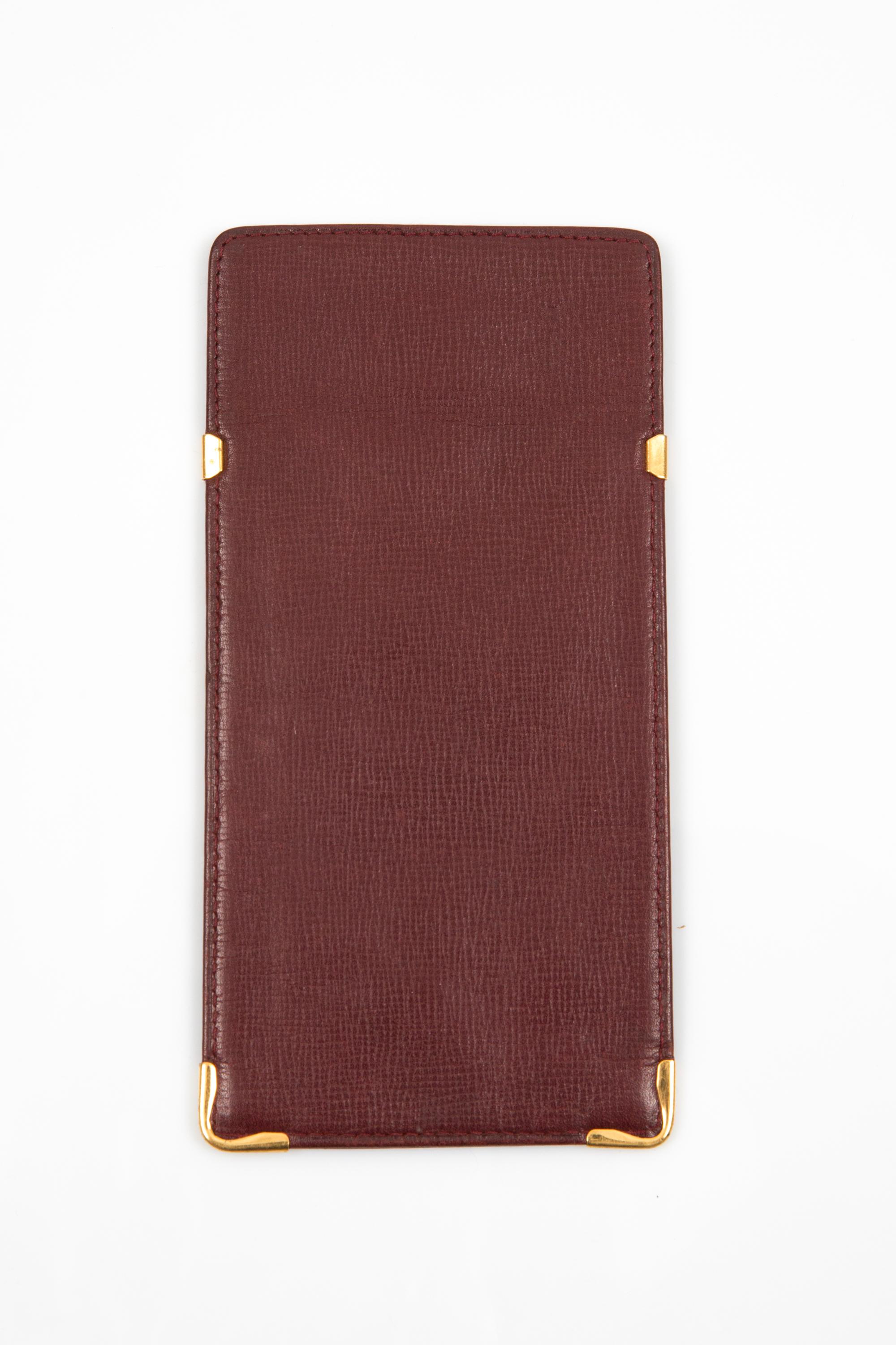 Custodia in pelle Cartier Bordeaux con angoli esterni placcati oro, logo esterno in rilievo e firma Cartier interna in pelle. 
Circa: anni '90
In buone condizioni vintage. Prodotto in Francia.
Lunghezza: 3,1 pollici (8 cm)
Altezza: 16,5 cm (6,4