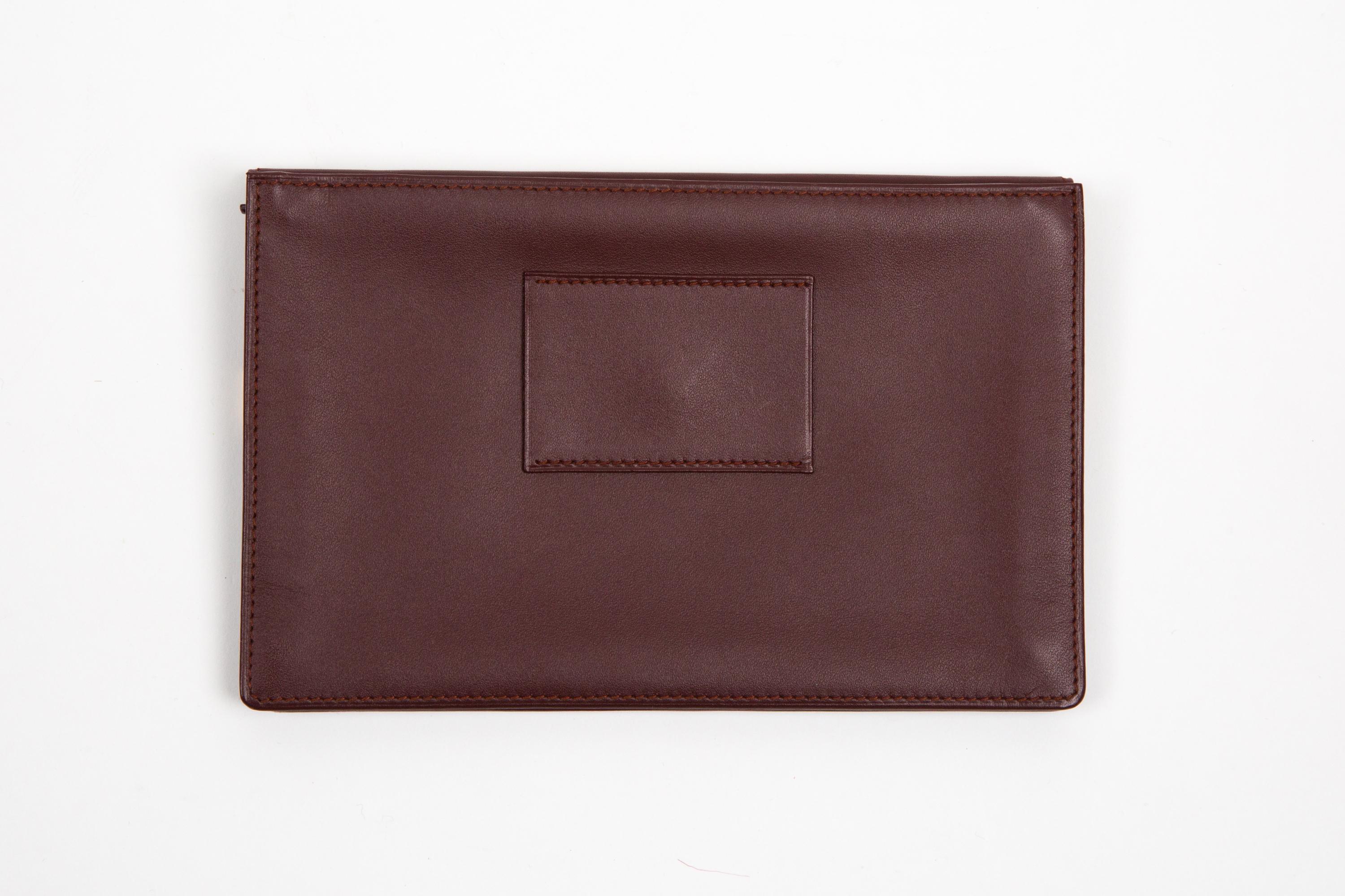 Pochette in pelle Cartier Bordeaux con passante posteriore, angoli placcati in oro, fodera interna con logo, apertura frontale a scatto, tasca posteriore con zip, timbro interno in tonalità oro, consegnata con scatola originale.
Circa: anni '90
In