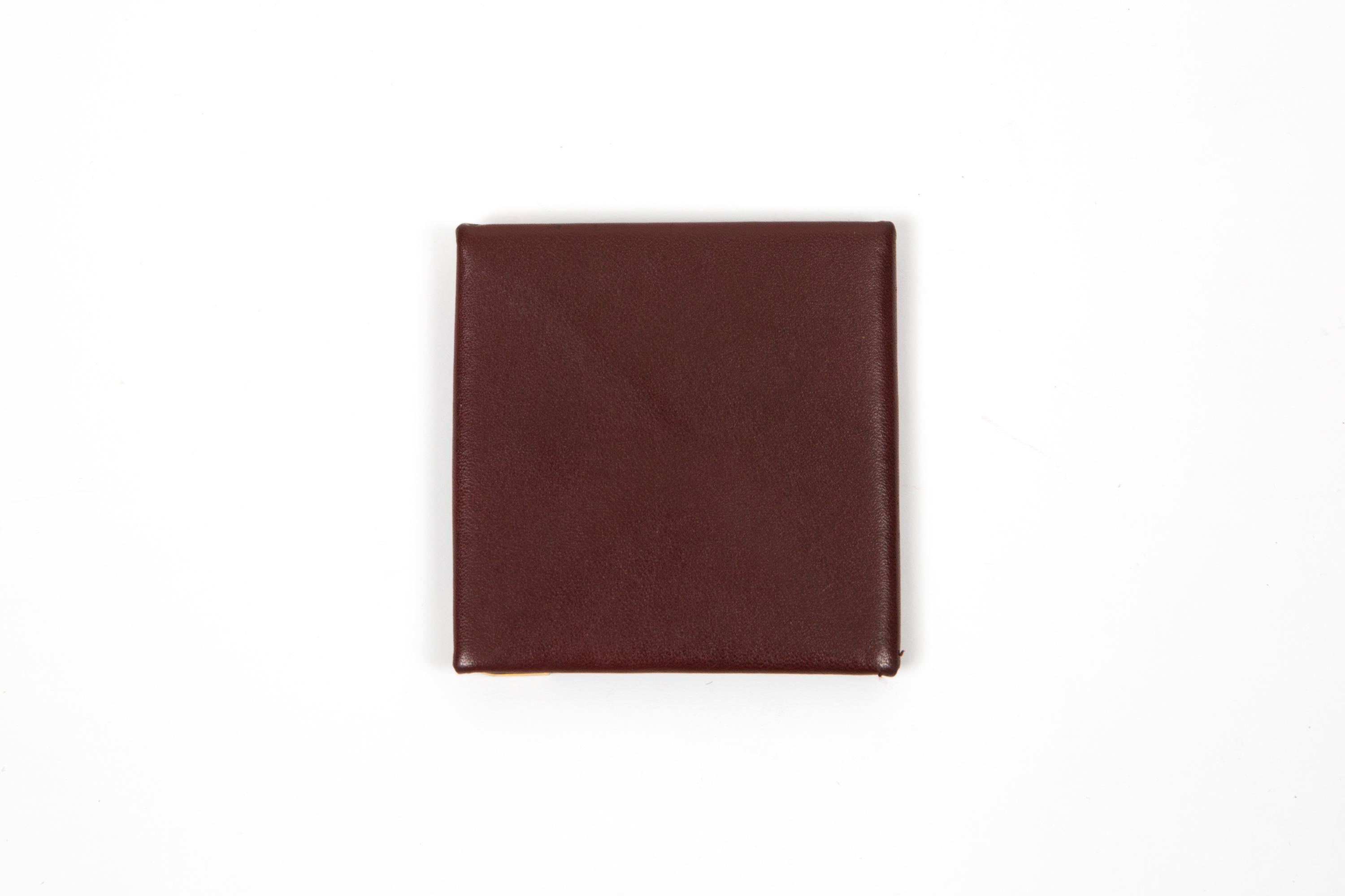 Cartier Bordeaux leather coin purse featuring gold-plated corners, inside a coin compartment, a snap closure and a golden hot-stamped Cartier signature. 
Circa: 1990s
In good vintage condition. Made in France.
3.1in. (8cm) X 3.1in. (8cm) X 0.39in