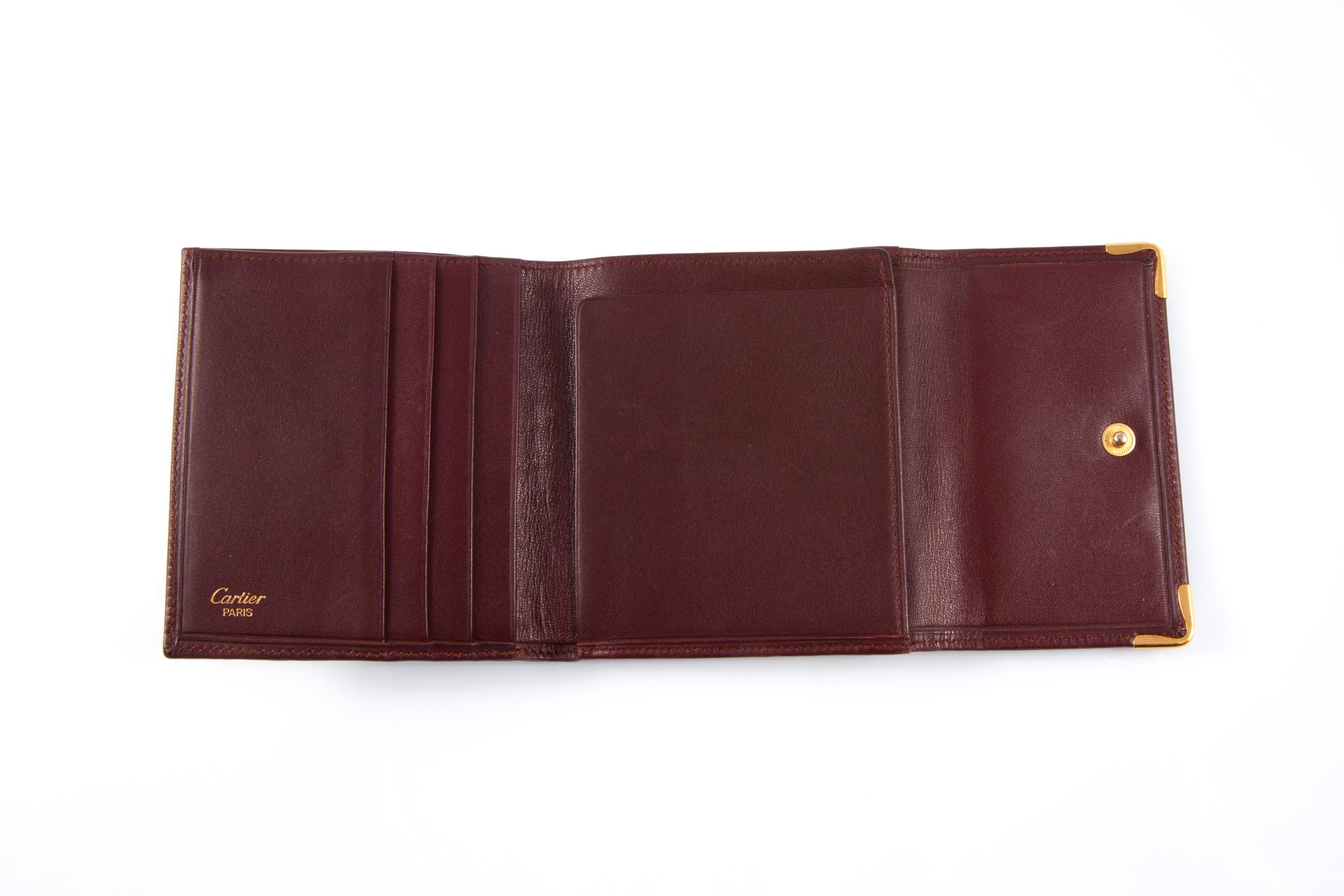 Cartier Bordeaux leather wallet featuring a back coin compartment with gold-tone claps opening, inside four credit card pockets and compartments and a golden hot-stamped Cartier signature. 
Circa 1990s 
In good vintage condition. Made in
