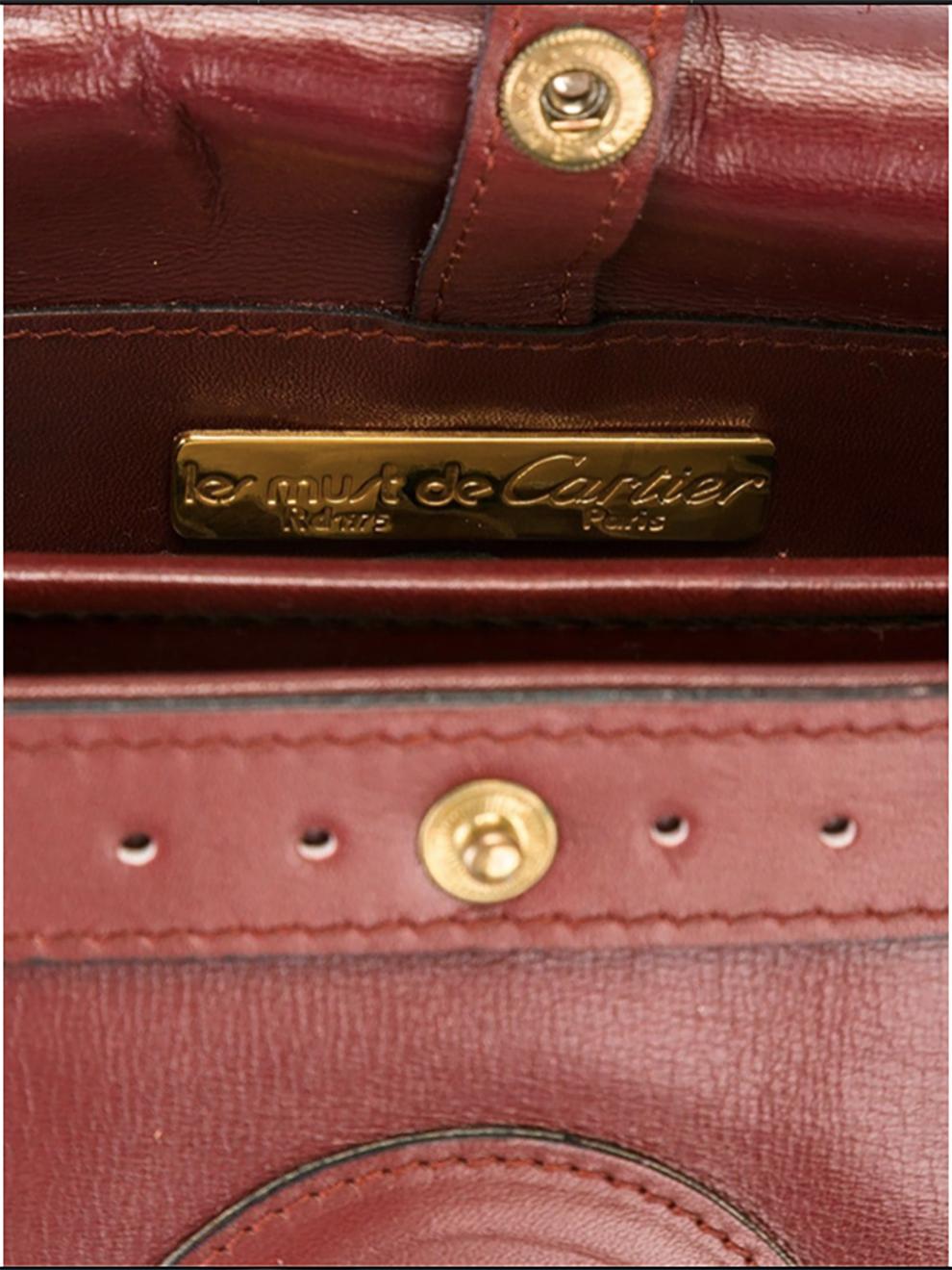 Cartier bordeaux suede and leather shoulder bag featuring gold-tone hardware and two inside compartments, a long adjustable shoulder strap ( 38,9 in. (99cm), an inside gold tone Must de Cartier plaque.
Width 11.4in. (29cm)
Height 8.2in. (21cm)
Width