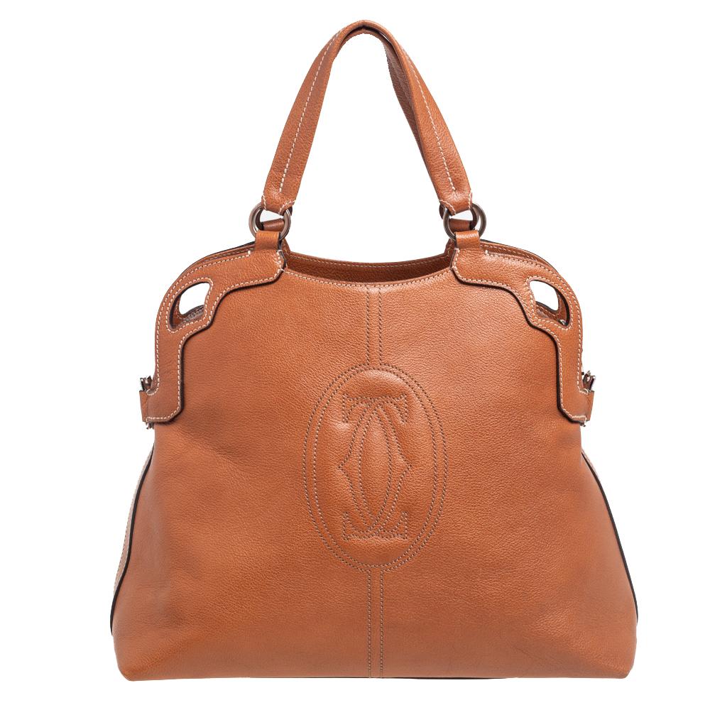This beautiful Marcello de Cartier satchel from Cartier arrives in a gorgeous shape and design. It is made from brown leather on the exterior and flaunts dual handles, silver-toned hardware, and a fabric-lined interior. It comes with a shoulder