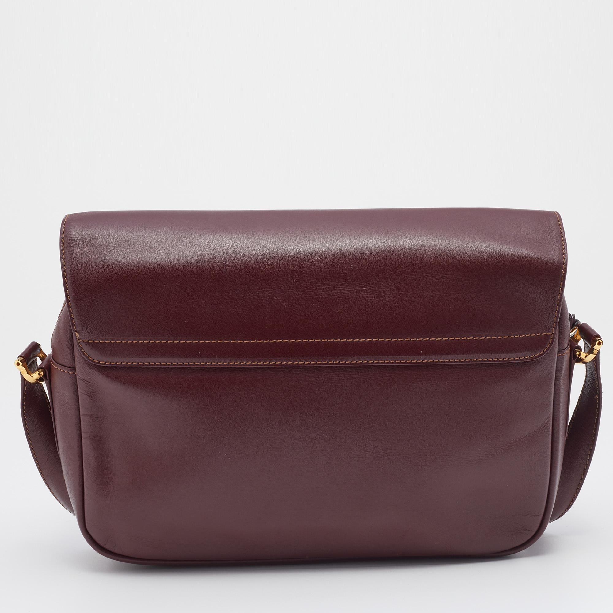 This Must de Cartier shoulder bag from Cartier is a luxurious piece worth adding to your closet. It is crafted from burgundy leather into a simple design with gold-tone hardware. It has a roomy fabric interior to securely house your