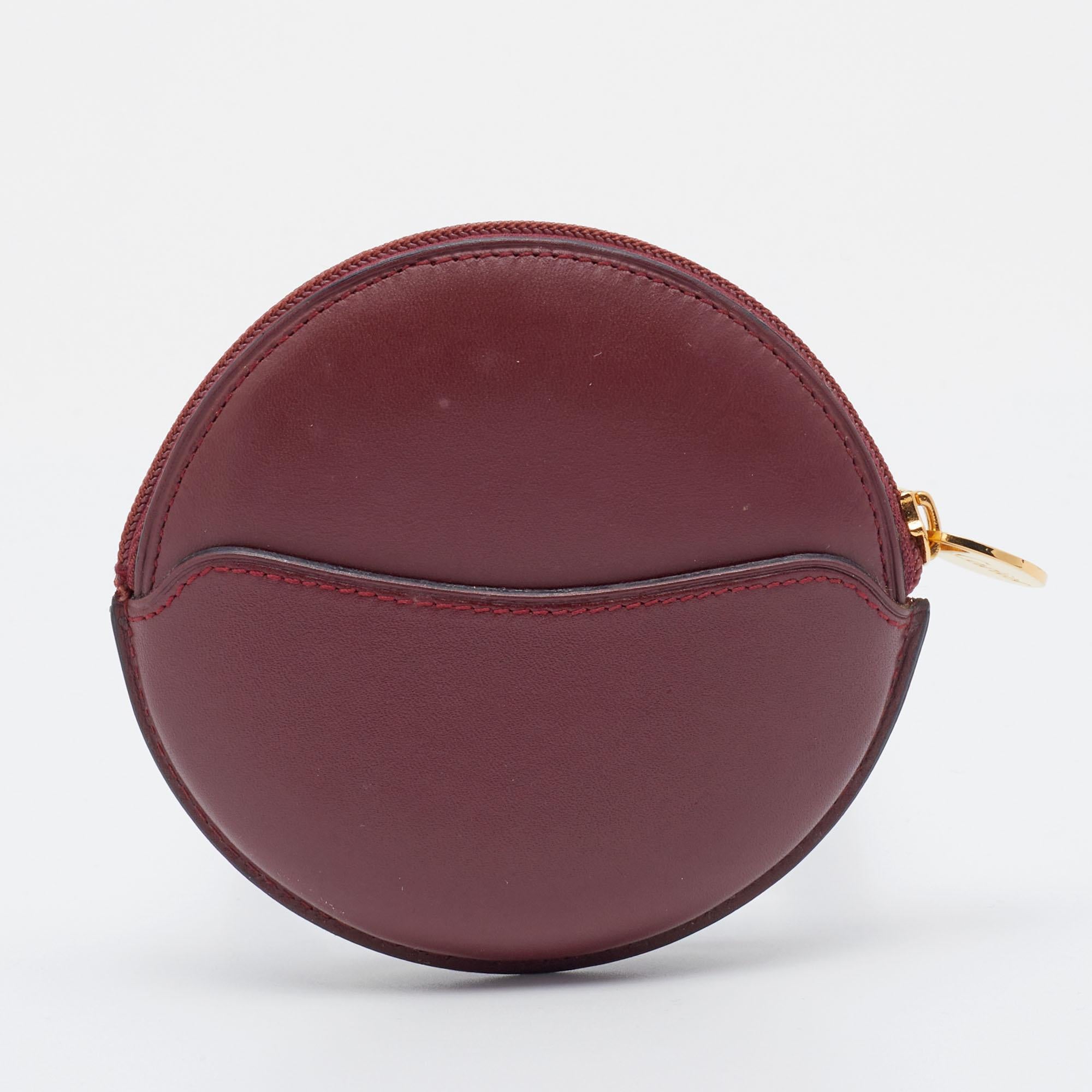 Designed into a round silhouette, this Cartier coin purse is a reliable accessory. It is created from leather and its interior is secured with a zipper closure at the top.

