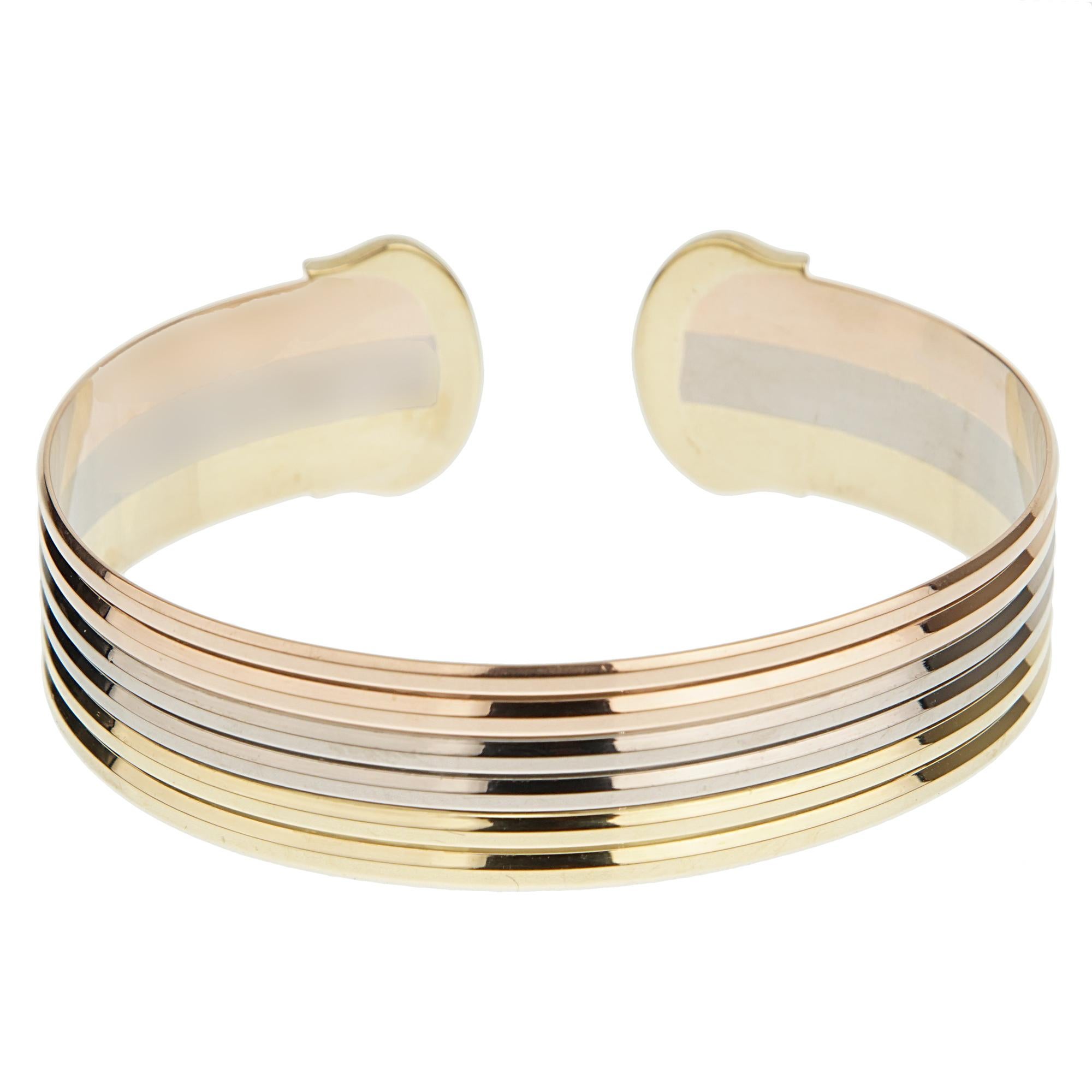 An iconic Cartier bracelet circa 1990s showcasing the C de Cartier motif ends with a trinity style cuff in 18k white yellow and rose gold. The bracelet will fit a 7