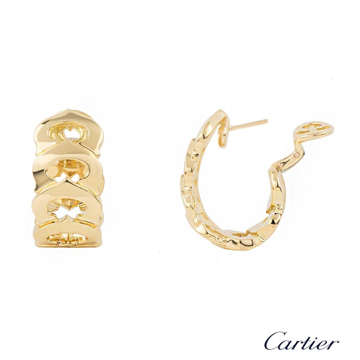 A pair of 18k yellow gold C de Cartier earrings. The hoops are composed of 7 interlinking iconic C de Cartier motifs fastened together with post and clip fittings. The earrings measure approximately 3cm x 1.5cm and have a gross weight of 32.30
