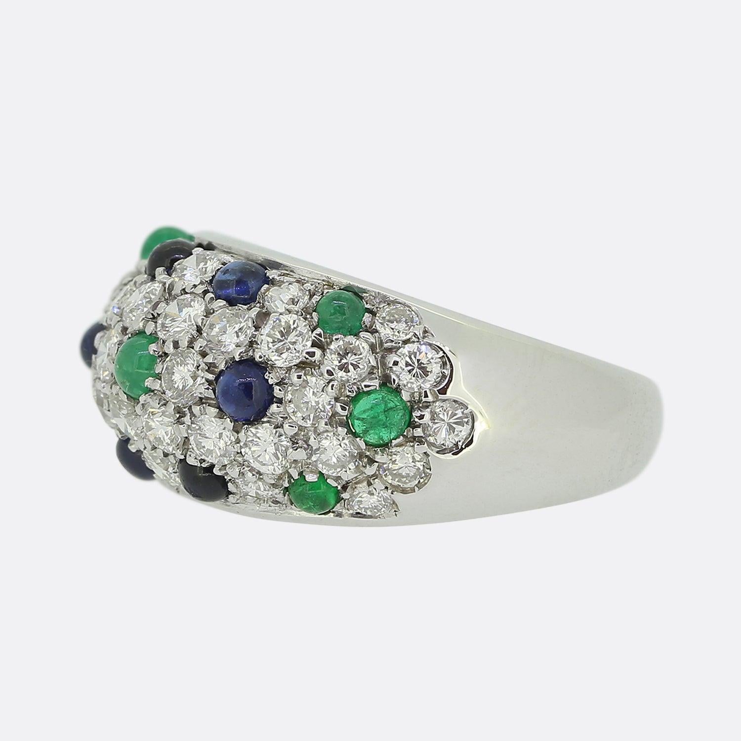 This is a wonderfully rare multi gemstone ring from the world renowned, luxury jewellery house of Cartier. This vintage piece has been crafted from 18ct white gold and showcases a pavé diamond set face with sequential cabochon sapphires and emeralds