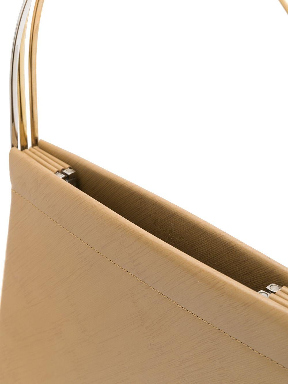 Crafted in France from pure camel-coloured leather, this classic Trinity cage bag is a true work of art by Cartier, featuring a slim silhouette, a discrete logo screen running diagonally throughout and three iconic round metal top handles in an