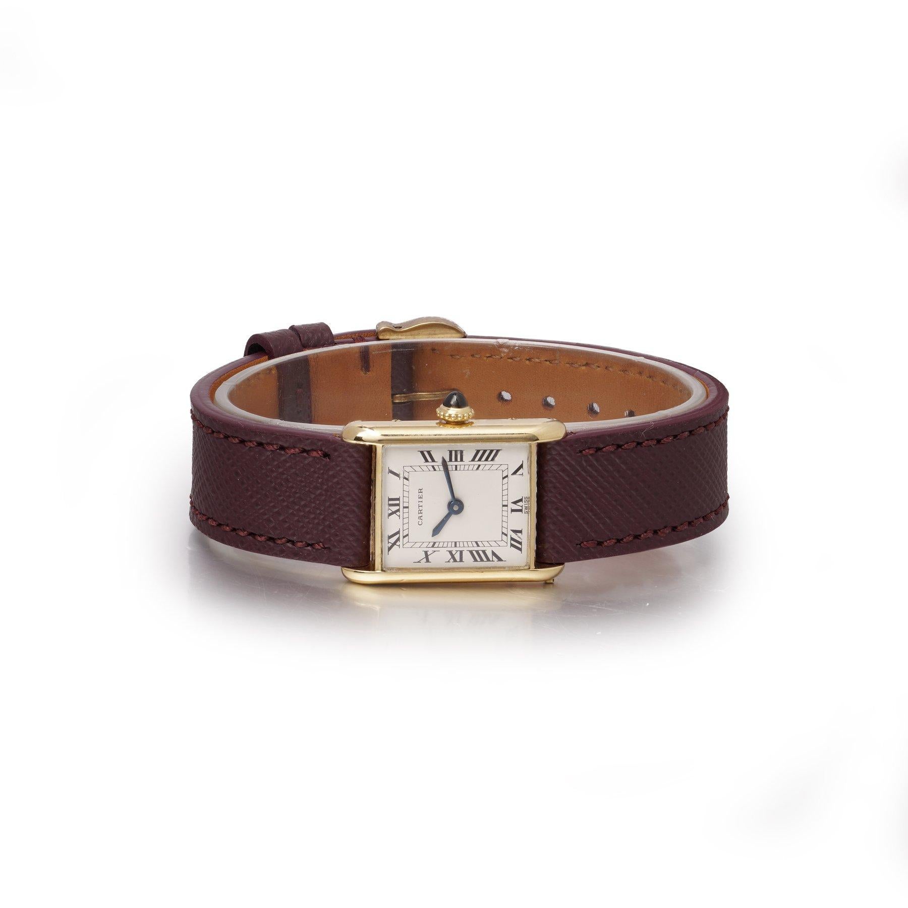 Un elegante Cartier Tank Louis Mini del 1986, con cassa rettangolare in oro giallo 18 carati, iconico quadrante con numeri romani e lancette a spada in acciaio blu. Il movimento a carica manuale è racchiuso in una raffinata cassa di 19 x 26 mm,