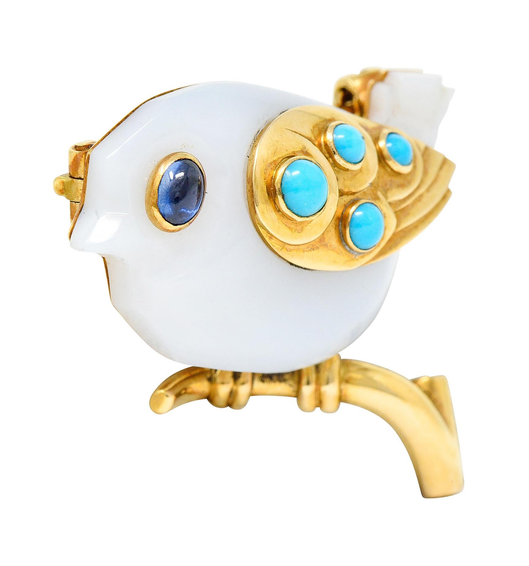 Designed as a stylized bird perched on a polished gold branch

Body is comprised of carved chalcedony - translucent and very light blue in color

With a gold wing accented by bezel set turquoise cabochons - brightly colored and well matched

Eye is