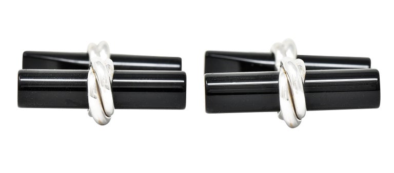 Bar style cufflinks with carved onyx terminals. Fashioned as cylinder forms - tapered and notched to secure in place. Each measures approximately 22.0 x 5.0 mm. Opaque black with excellent polish. Set in a twisted cable forms. Stamped 750 for 18