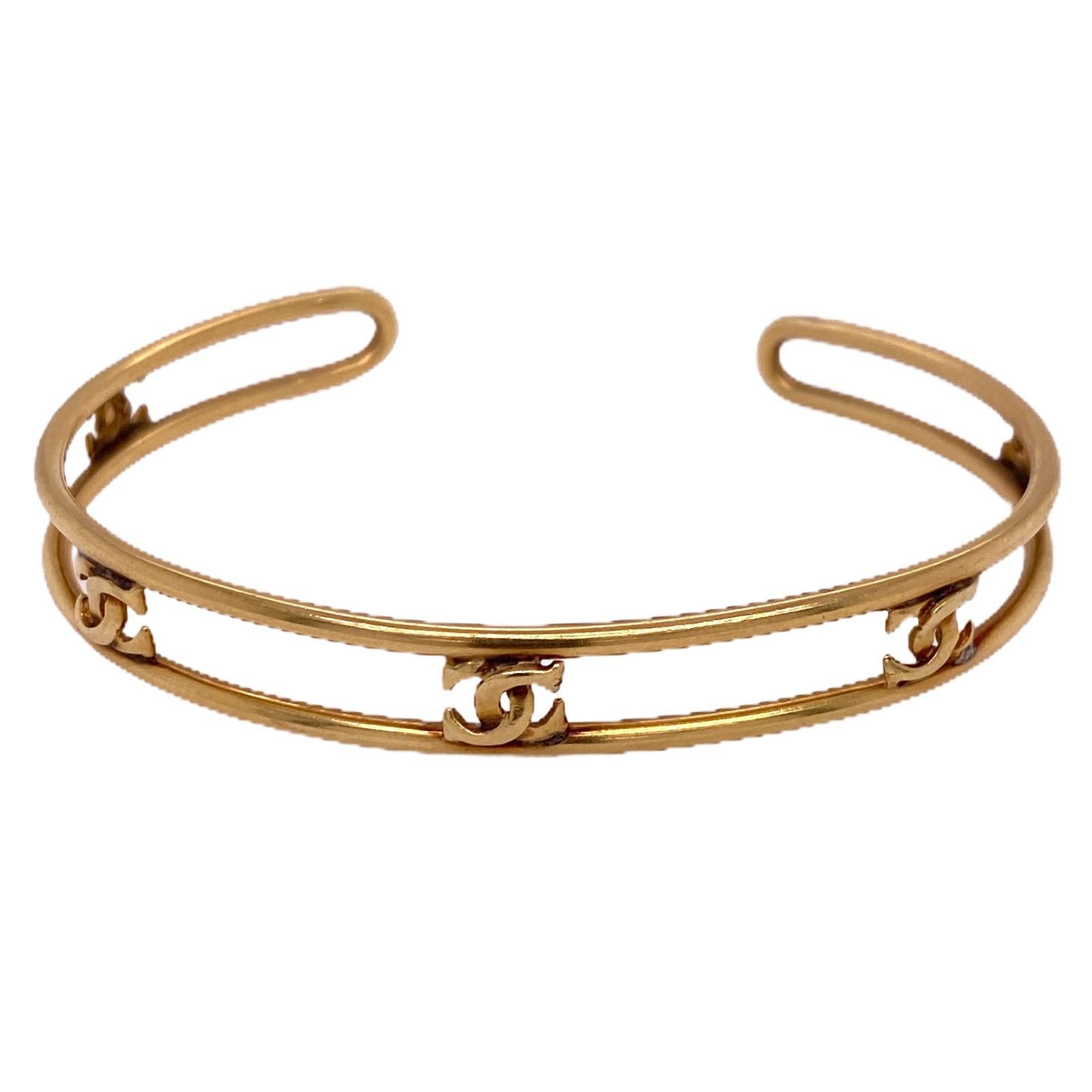 Cartier cuff circa 1980-1990 is hand crafted in 18 karat yellow gold. The bracelet features Cartier's CC logo in an open design cuff. The bracelet measures 2.25 inches in diameter, 6.5 inch circumference, .25 inches in width, and is signed Cartier