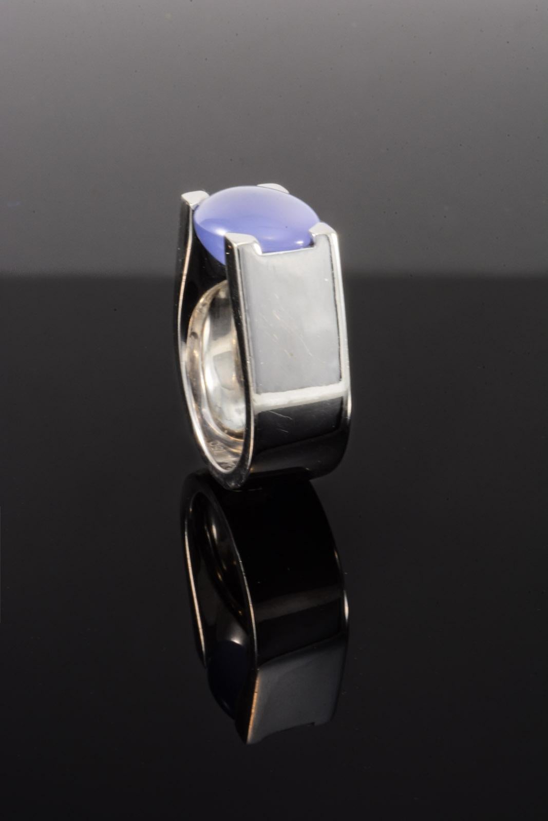 This is a genuine signed Cartier oval Baby Blue Chalcedony designer Ring. It is expertly hewn from solid high polish 18 karat white Gold and features a thick flat edge shank with great heft that lets you know you're wearing quality. In the center