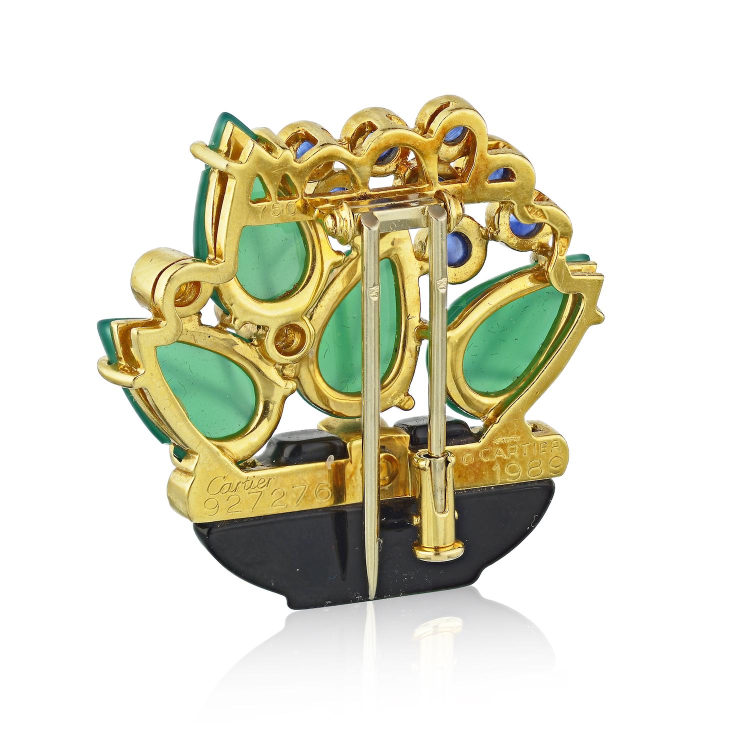 This is a listing for 2 exquisite brooches from Cartier's celebrated Les Indes Galantes collection features a floral design composed of a black onyx bowl accented with full-cut paved diamonds, green curved agate leaves, round cabochon blue sapphires