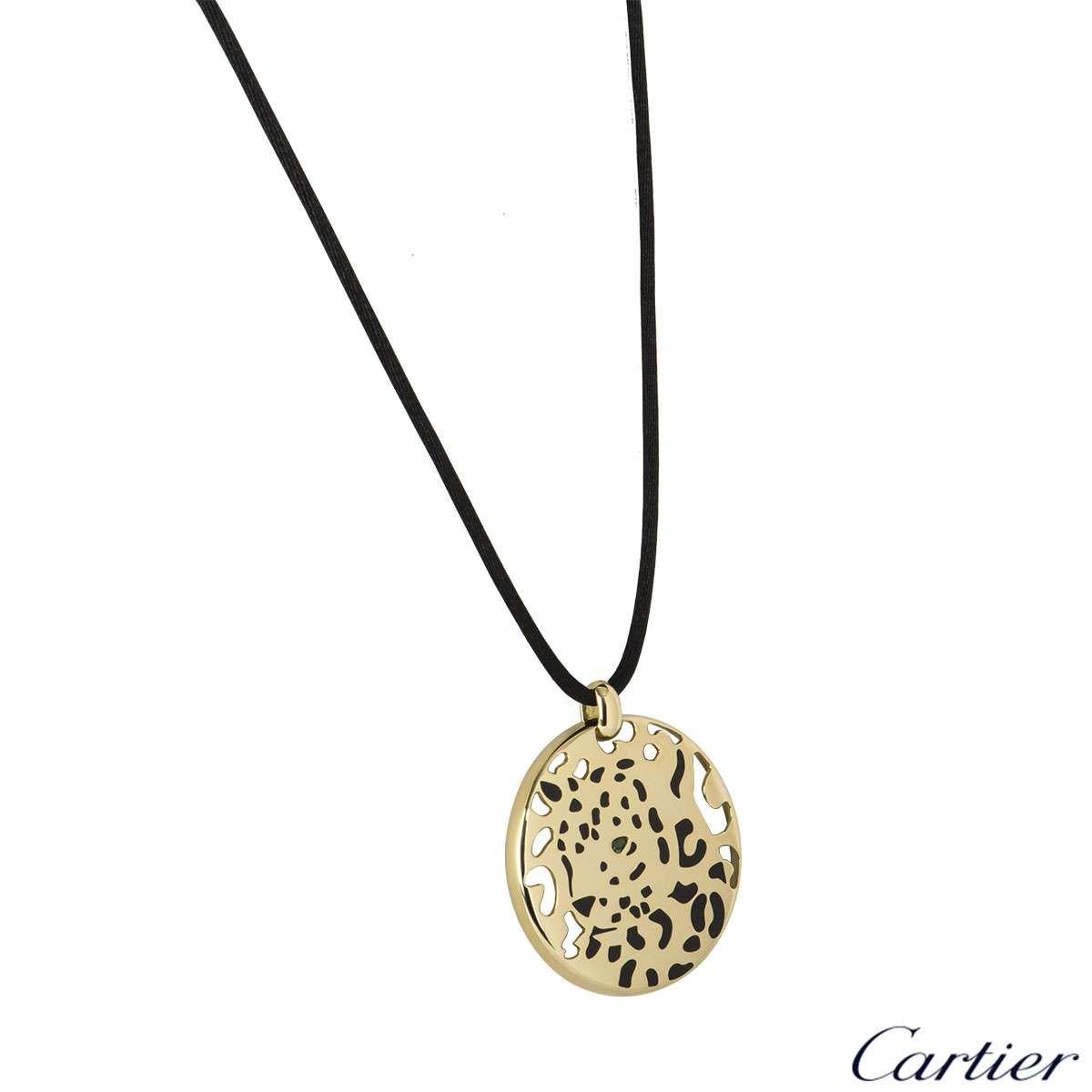 A stunning 18k yellow gold Cartier necklace from the Panthere collection. The necklace features a circular motif with a panther in the centre shaped from black lacquer, complete with a single tsavorite garnet as the eye. The circular motif measures