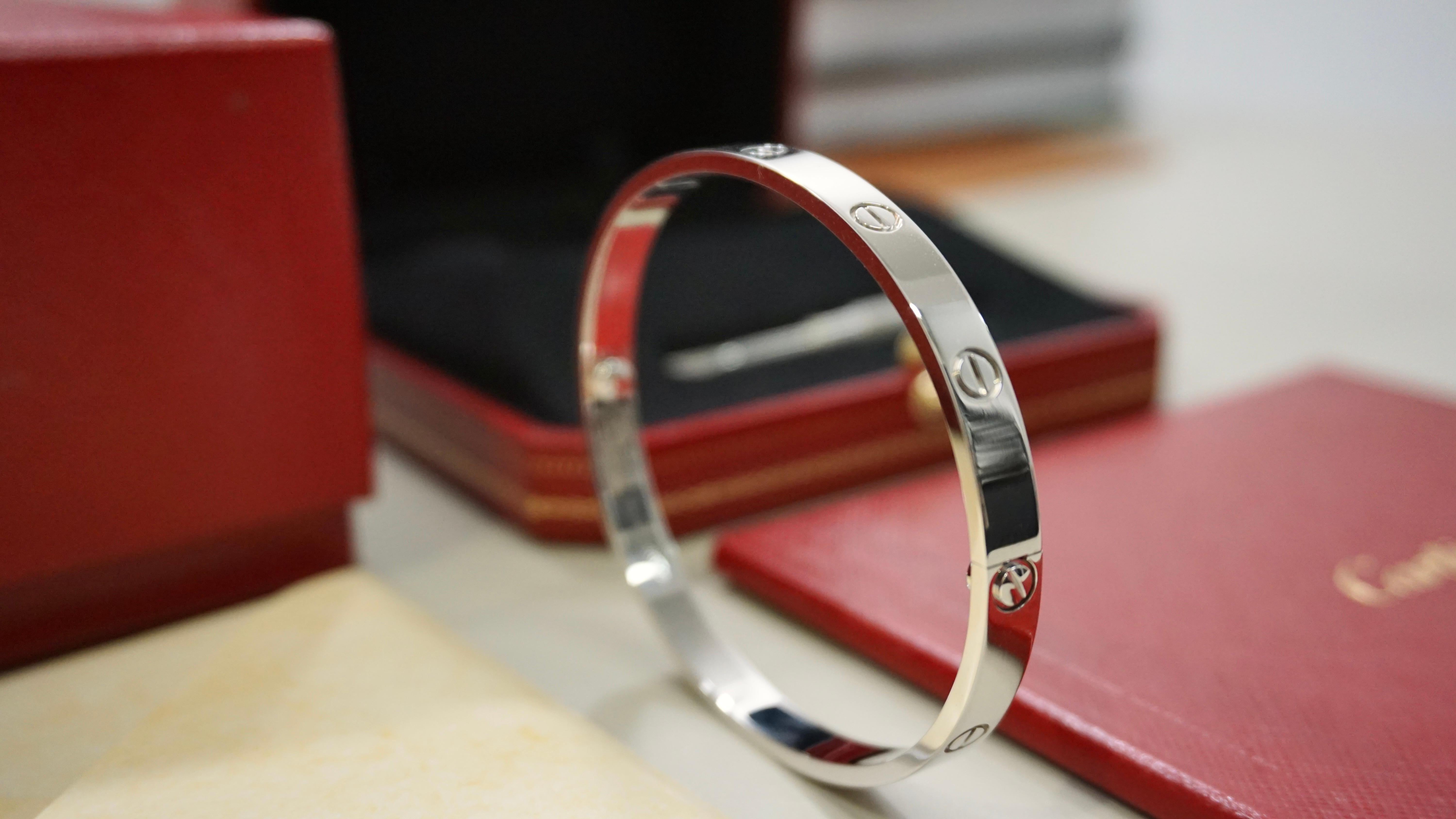 Questo braccialetto Cartier Love di dimensioni classiche è uno splendido gioiello realizzato in oro bianco. Il bracciale ha una forma ovale con chiusura a vite ed è dotato di marchio di fabbrica. L'articolo è di colore oro bianco e misura 20 cm di