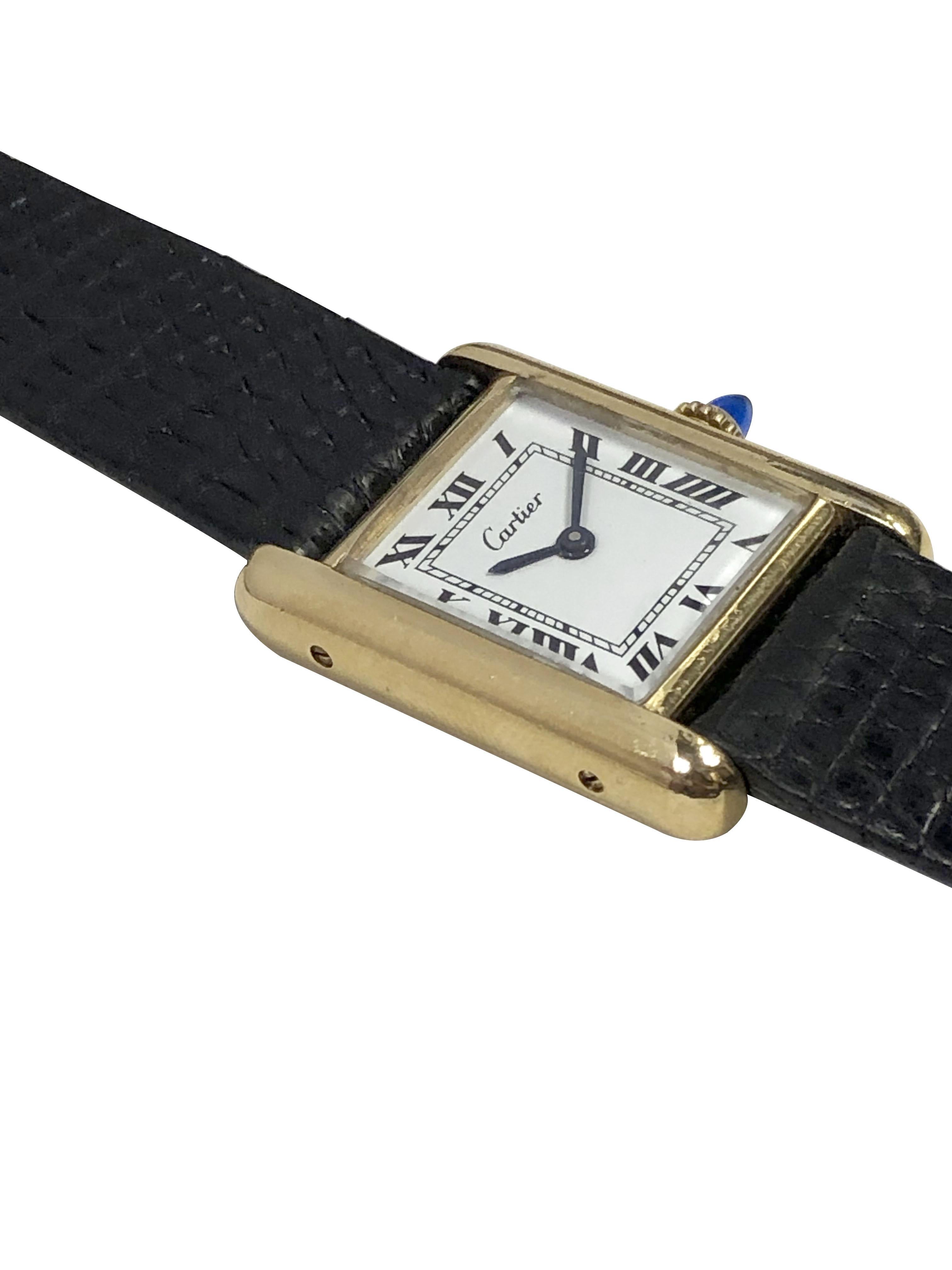 Circa 1980s Cartier Ladies Wrist Watch, 28 X 20 M.M. 2 Piece Gold Plaque Case,17 Jewel Mechanical, Manual wind movement, Sapphire Crown, White Dial with Black Roman Numerals. New Black Lizard Strap. Wrist length 8 inches. Comes in a Cartier Travel