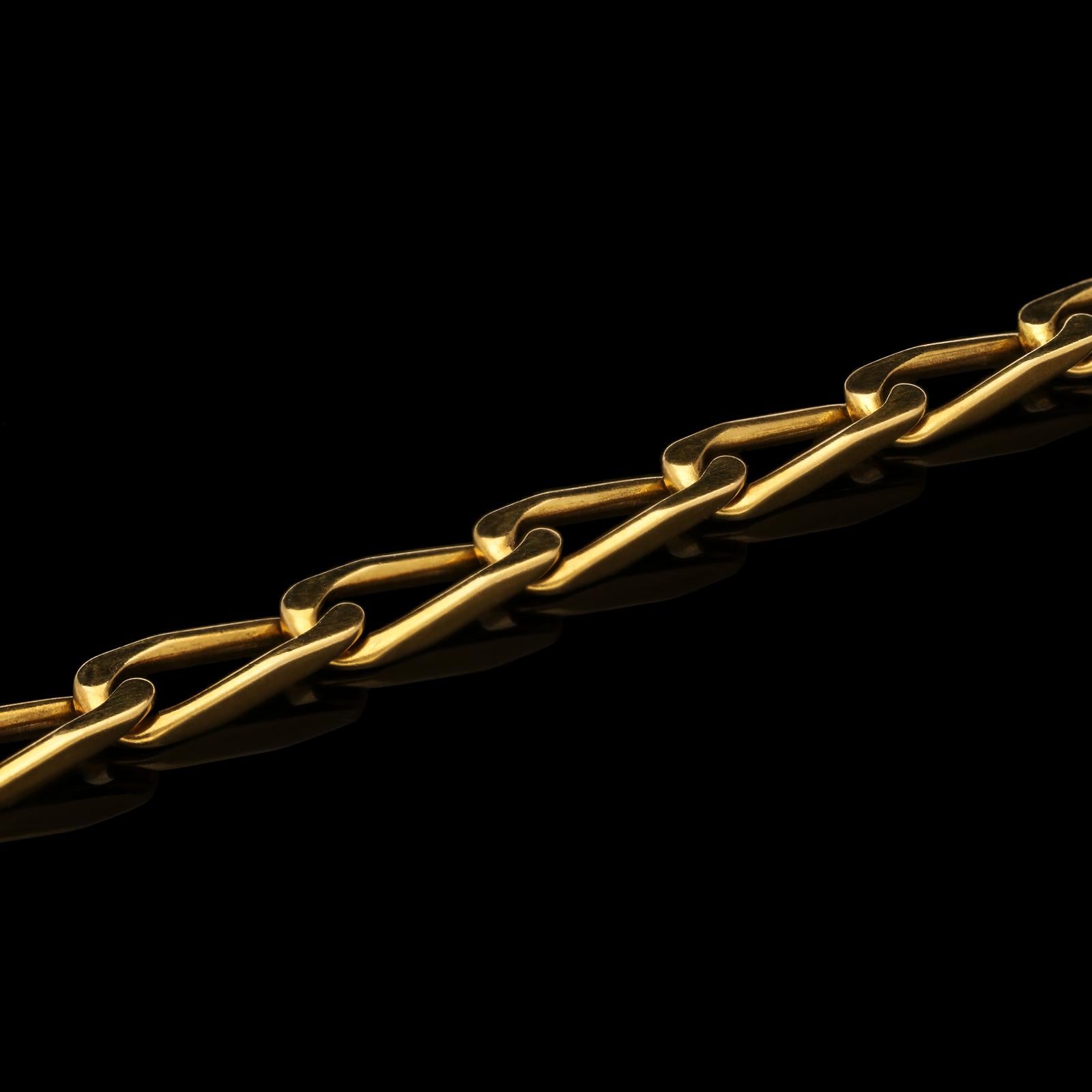 A classic gold paper clip chain necklace by Cartier 1976, the long chain measuring 39.5 inches long and formed of uniform oval links of paper clip inspired design which have a slight twist to them allowing the necklace to sit perfectly flat, to a