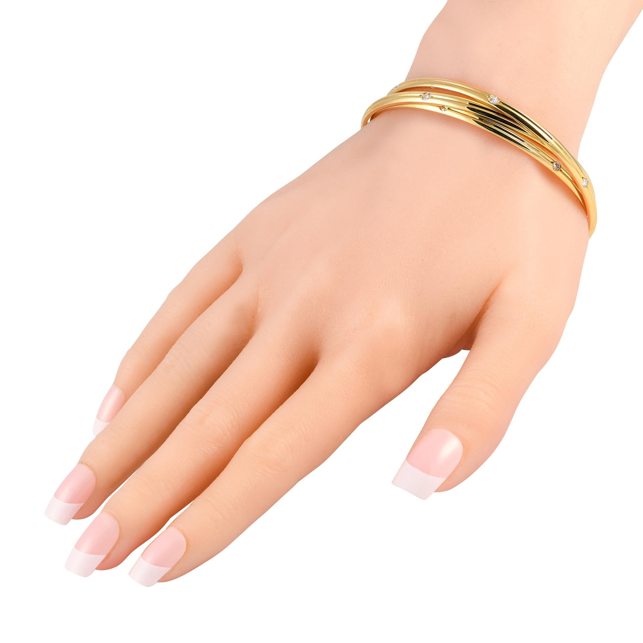A trio of 18K Yellow Gold bangles are delicately intertwined on this exquisite Cartier Constellation bracelet. Timeless and incredibly chic, this piece measures 7.85 long and features inset Diamond accents with a total weight of 1.0 carats.This
