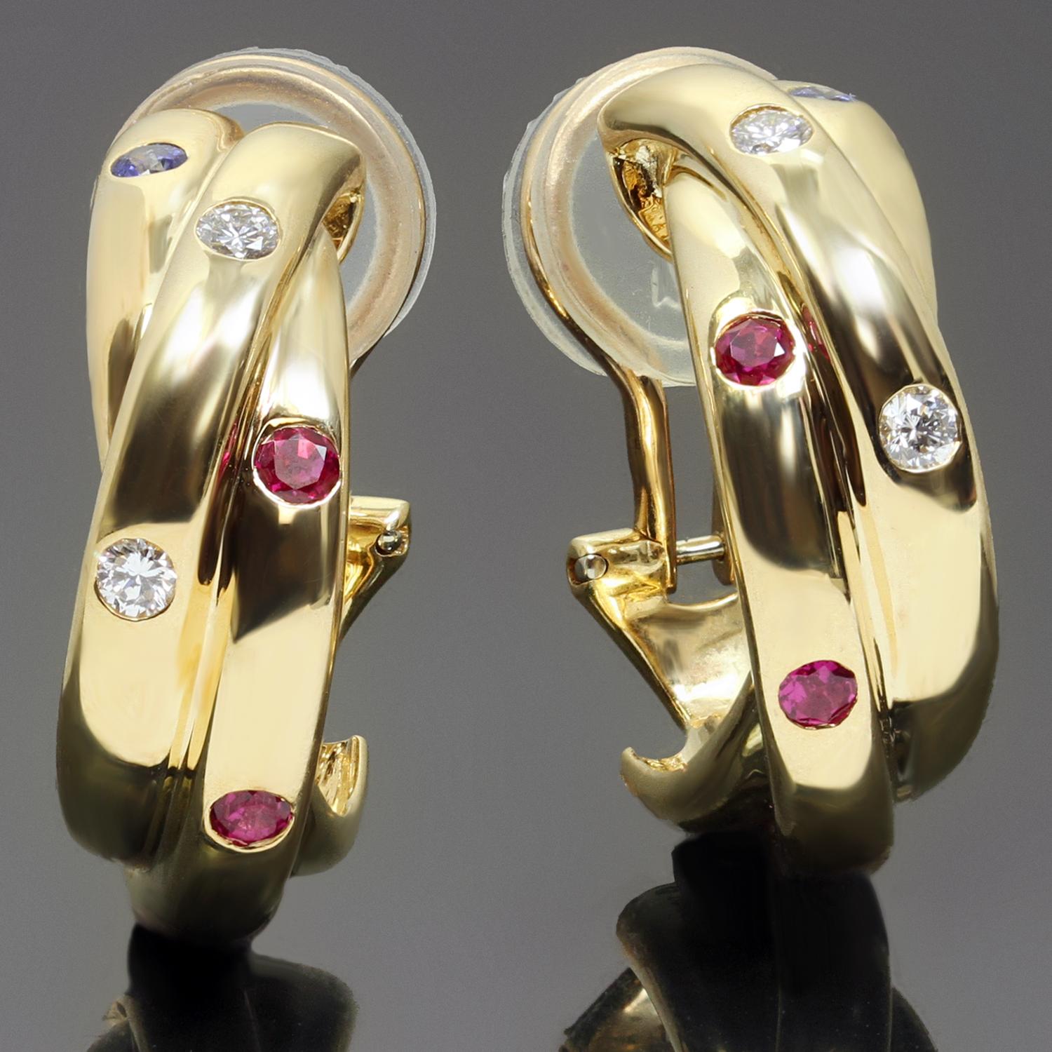 These gorgeous Cartier lever-back clip-on wrap earrings from the classic Constellation collection feature intertwined bands crafted in 18k yellow gold and set with red rubies, blue sapphires, and brilliant-cut round F-G VVS1-VVS2 diamonds weighing