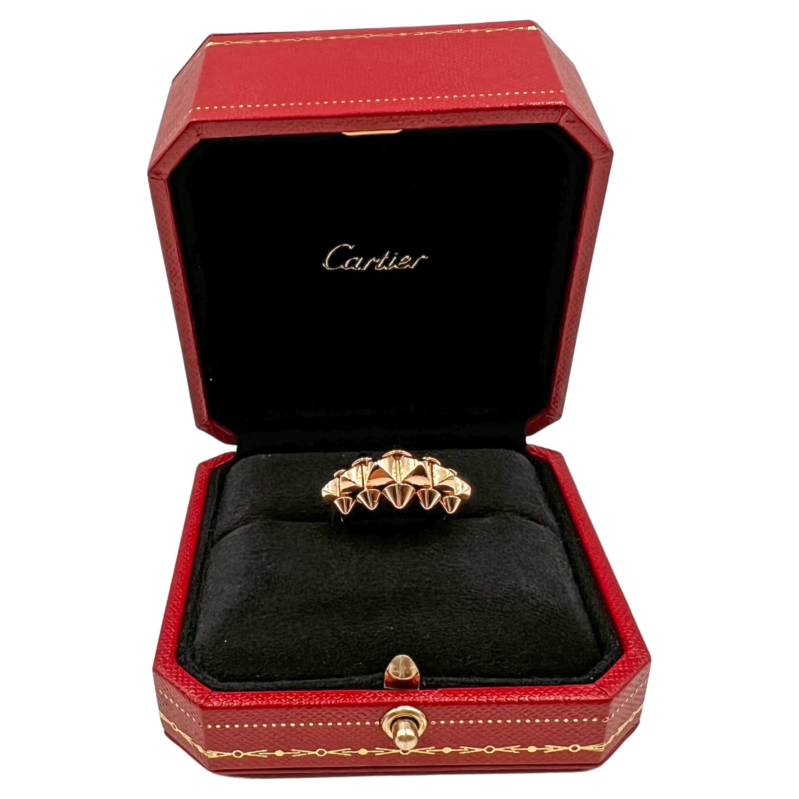 This 18k rose gold medium-sized version of the de Clash de Cartier ring includes the signature row of clou carré studs halfway down the band and a solid polished shank at the bottom. The central row has six larger pyramidal graduated studs bordered