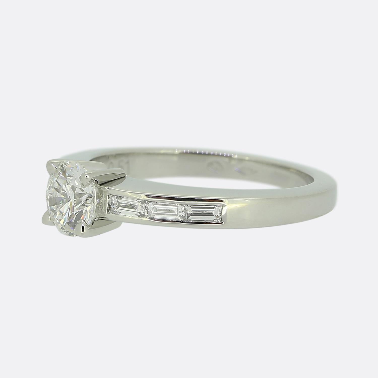 Here we have a delightful engagement ring from the world renowned luxury jewellery house of Cartier. This platinum piece features a single bright white round brilliant-cut diamond at the centre of the face. This principal stone sits slightly risen
