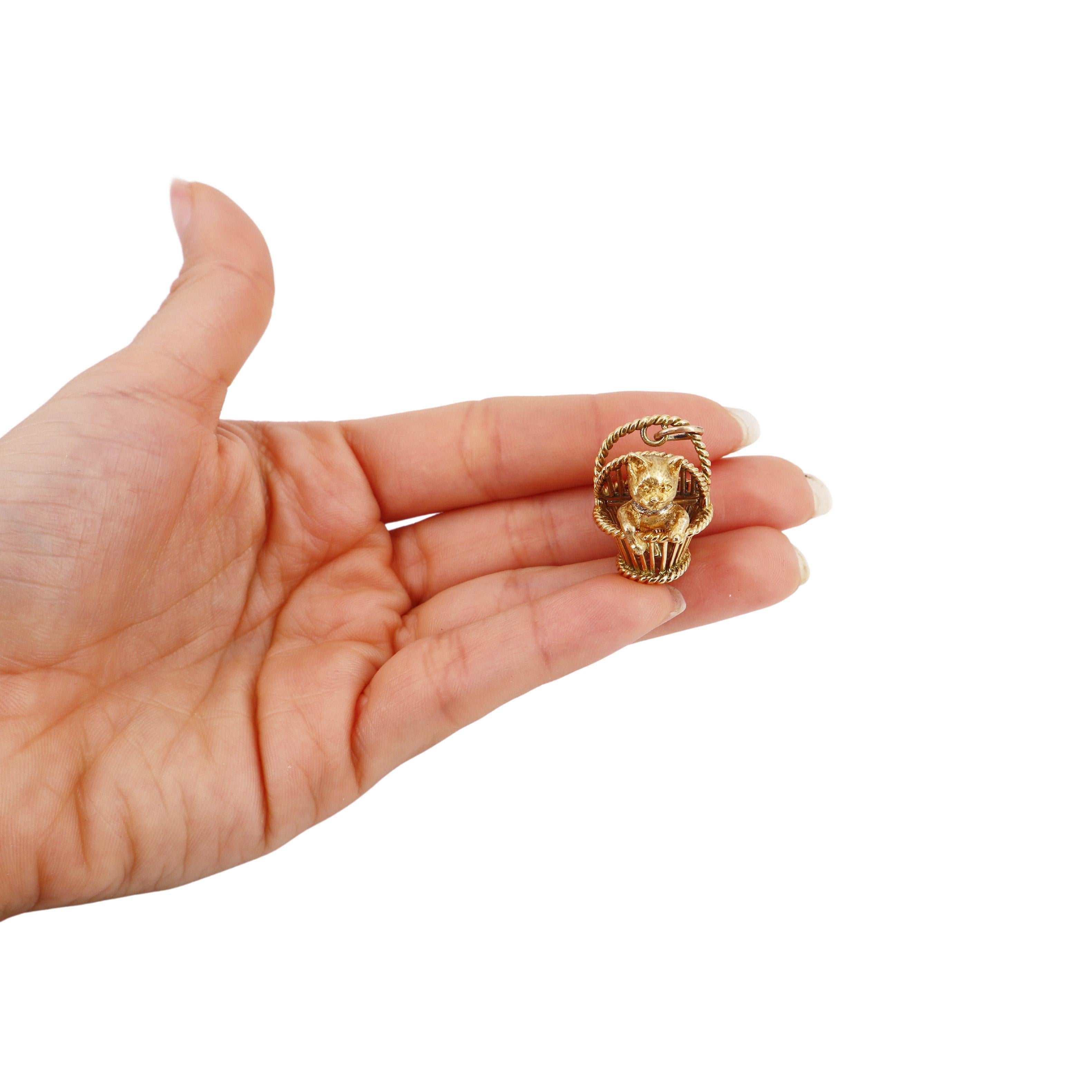 This enchanting 18-karat yellow gold pendant showcases a beautifully crafted basket design, elegantly housing a delightful kitten motif. The jeweler's exceptional metalworking skills are evident in the intricate latticework of the basket, which